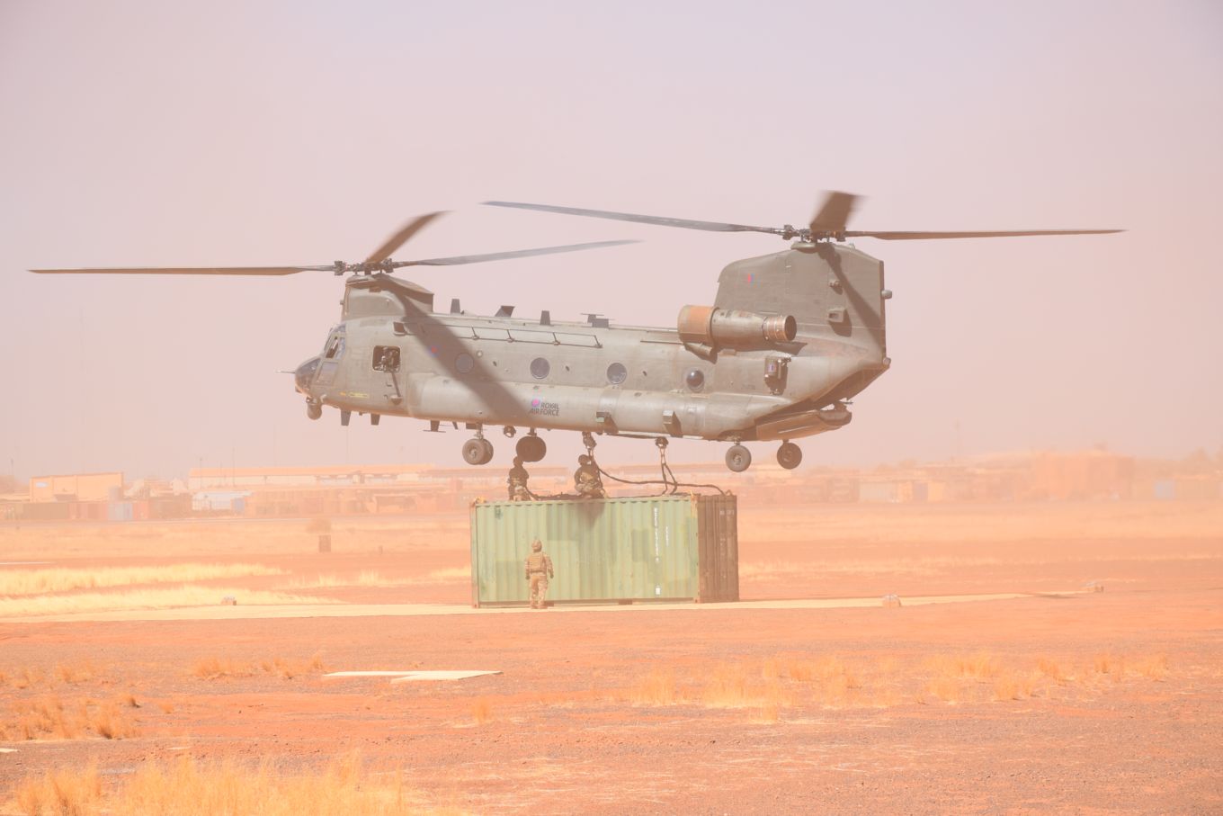 Image shows RAF Chinook in the desert landing the container on the ground.