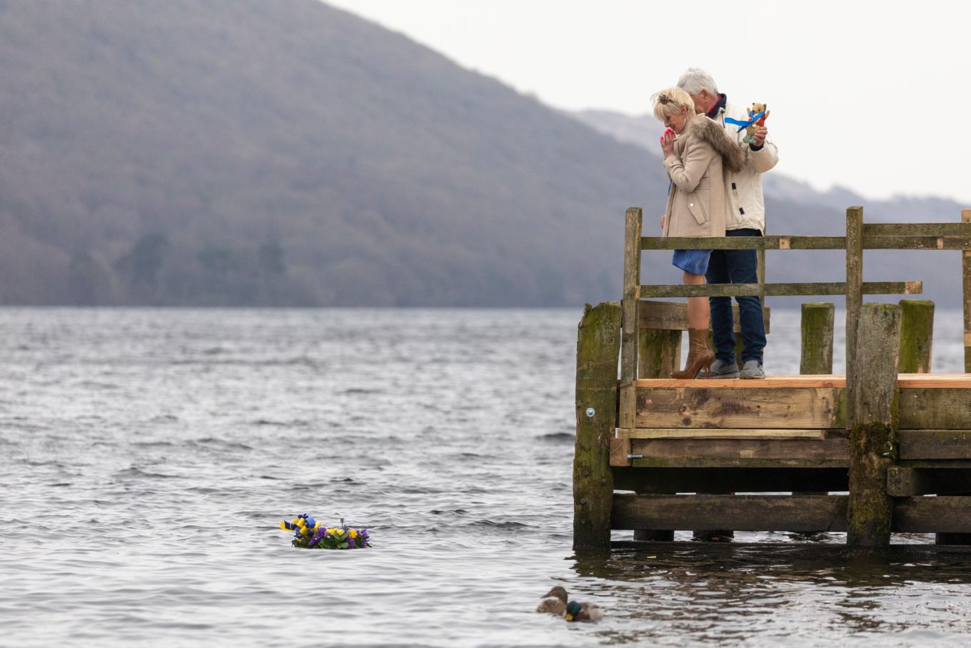 Image shows Donald Campbell's daughter on a dock after laying a bunch of flowers in the lake.