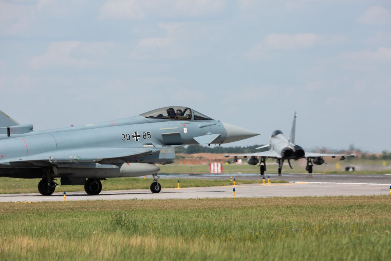 Image shows an RAF Typhoon and a German Eurofighter taxiing on the runway.
