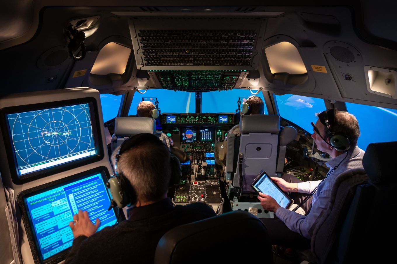 Four personnel train in a C-17 Globmaster aircraft cockpit simulator.