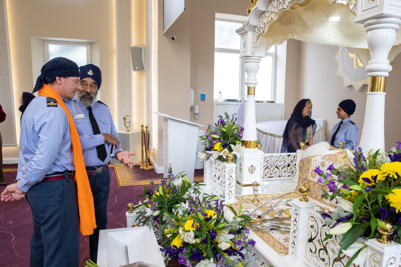 Chief of Air Staff looks on at an ornate chair display and flowers in the temple. 