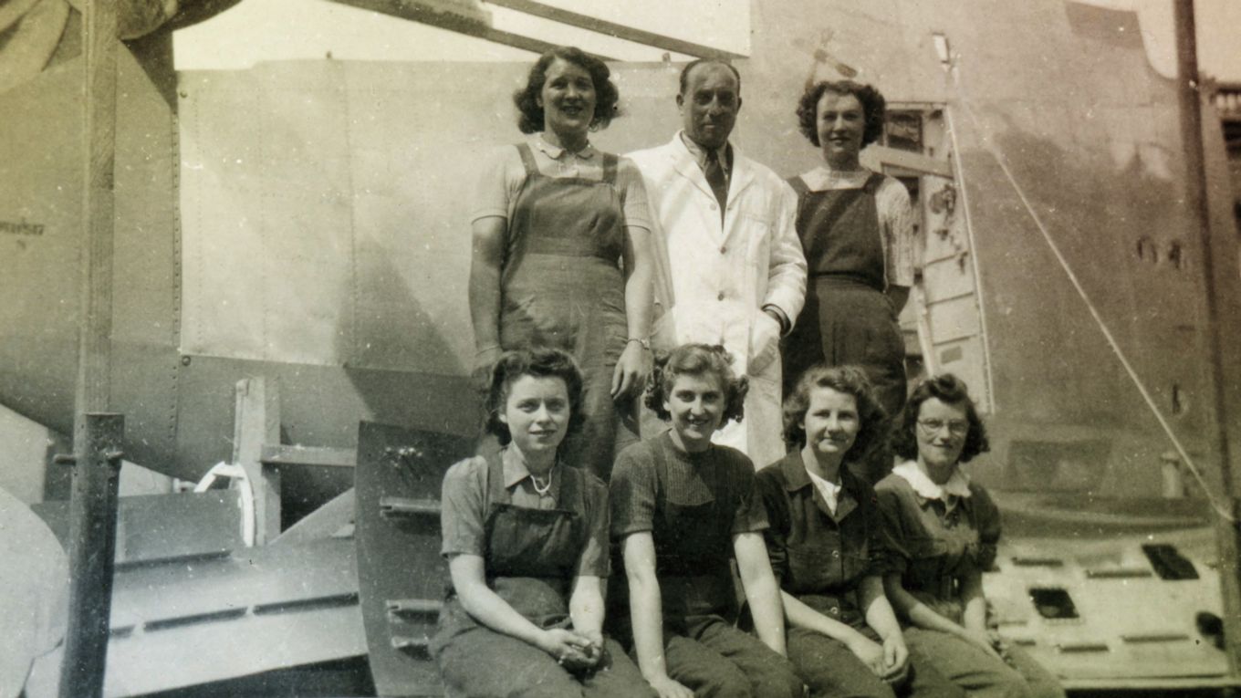 A black and white photo of female Secret Spitfire builders by a Spitfire. 
