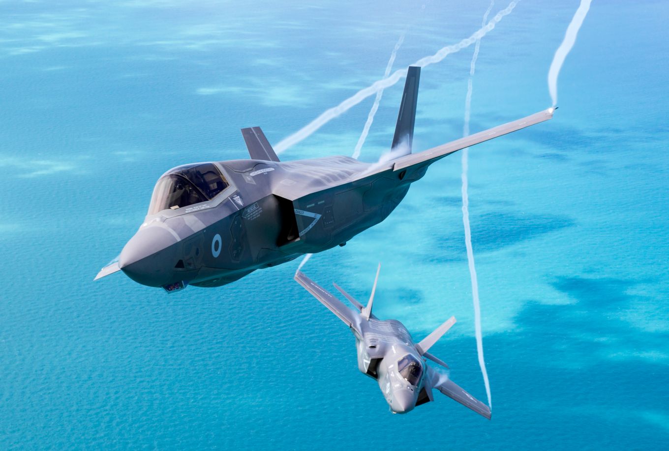 Image shows two F-35 Lightning aircraft flying above the sea.