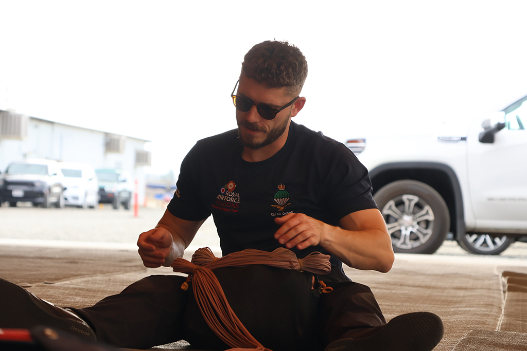 Corporal Edmund Dyson packing a parachutes rigging lines.