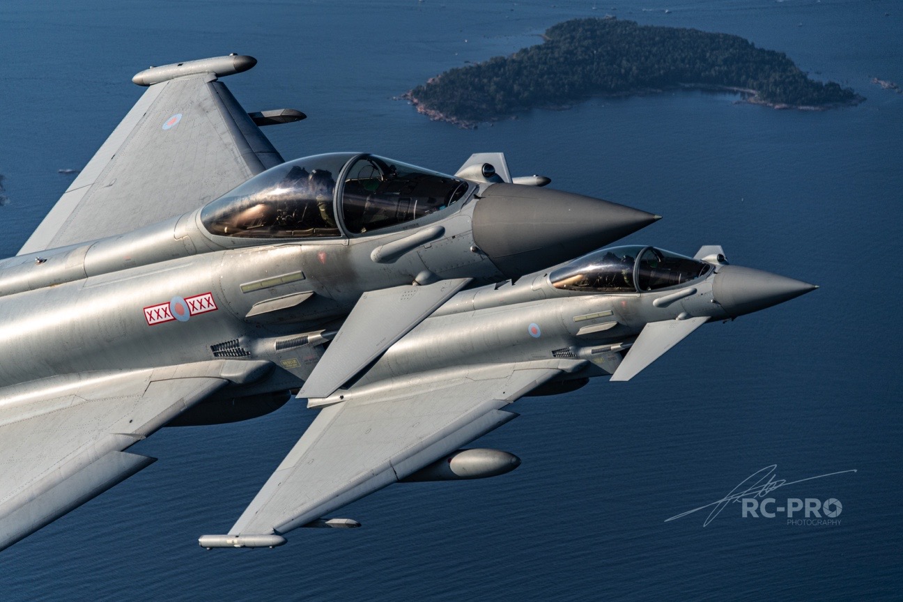 Two Typhoon in flight with island in the background.
