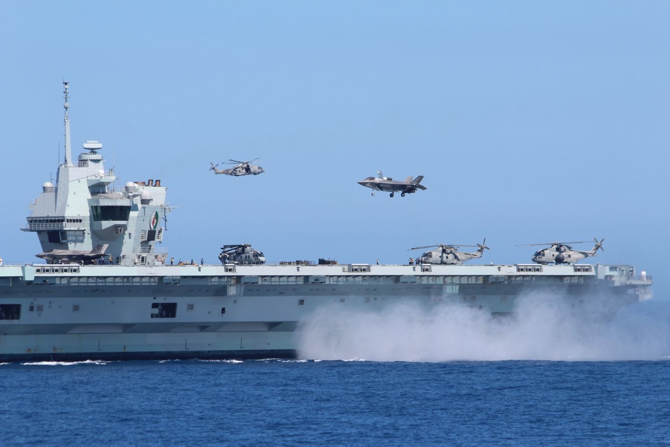 Aircraft carrier with Royal Navy Merlin's and F-35B Lightnings taking off.