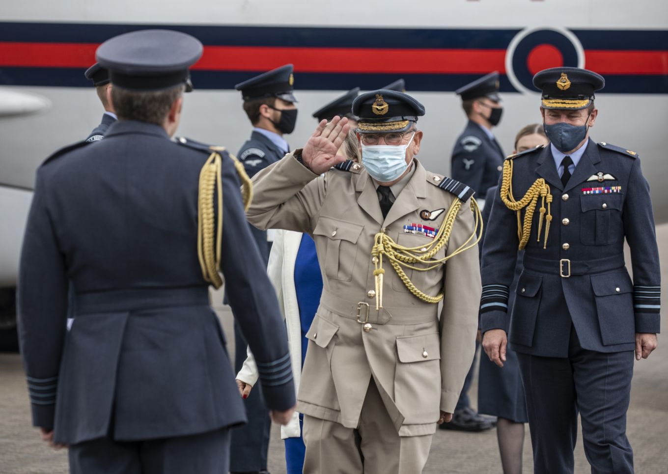 Air Chief Marshal Sir Stuart Peach salutes gathered personnel. Aircraft in background. 