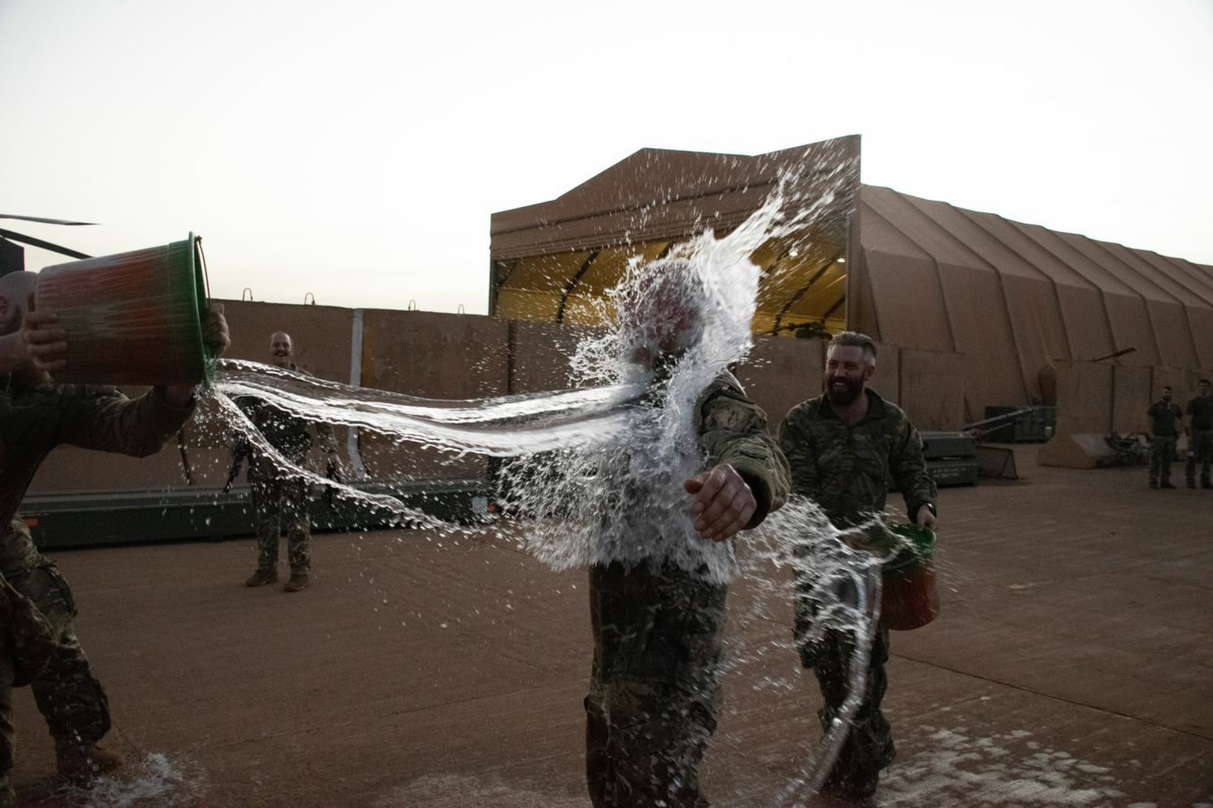 Master Aircrew Ruffles being soaked by three other personnel with buckets of water.