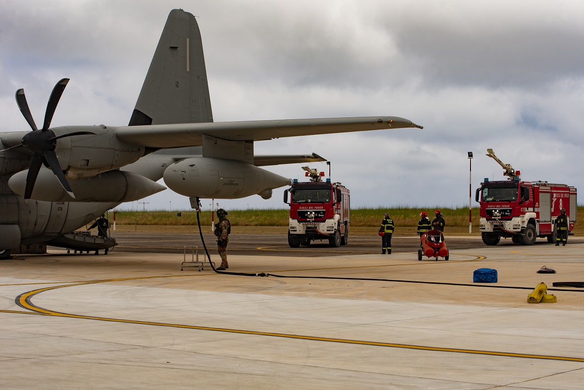 A KC-130J tanker with two fire engines and personnel. 