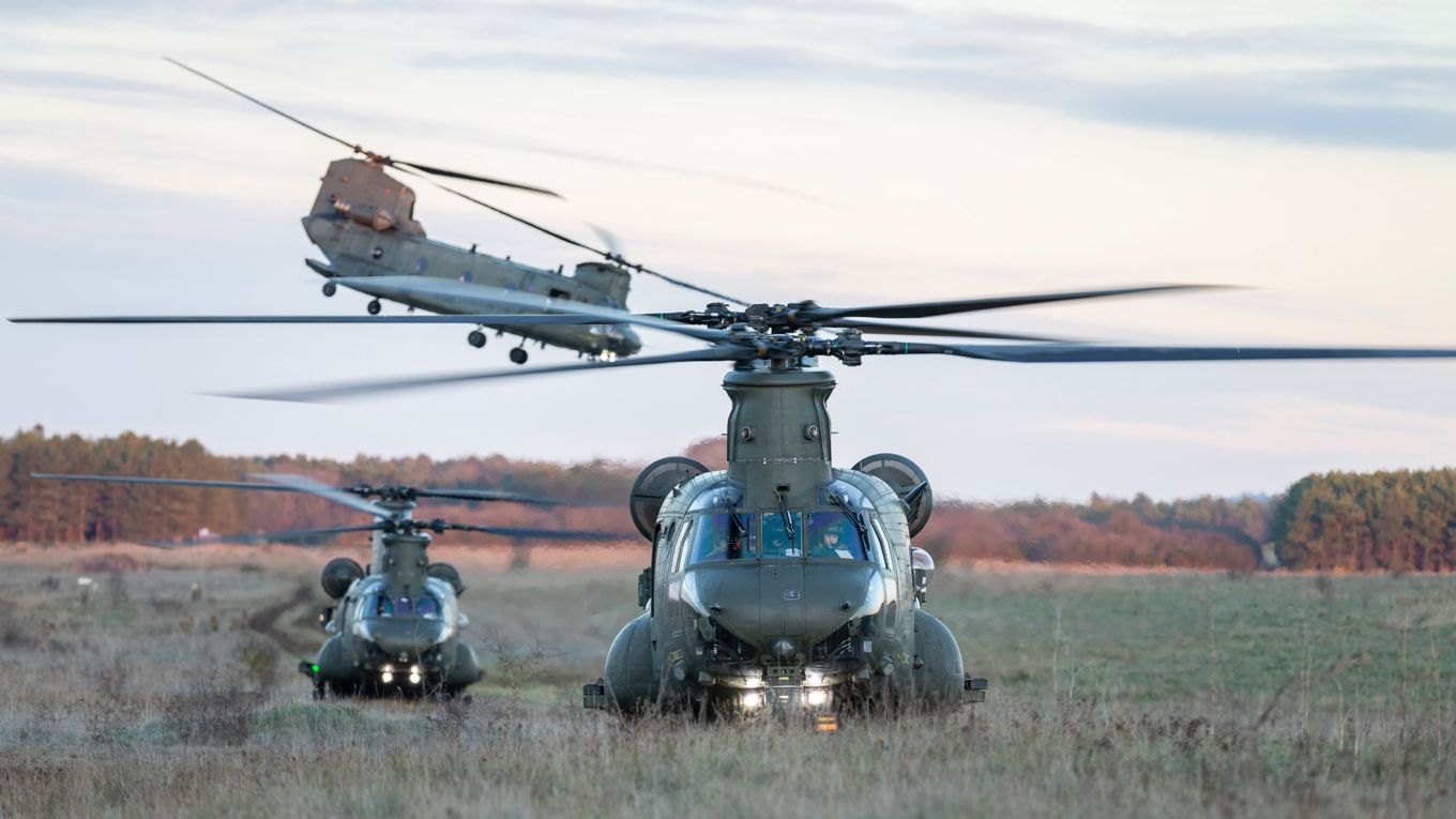 3 chinook aircraft landing in a field