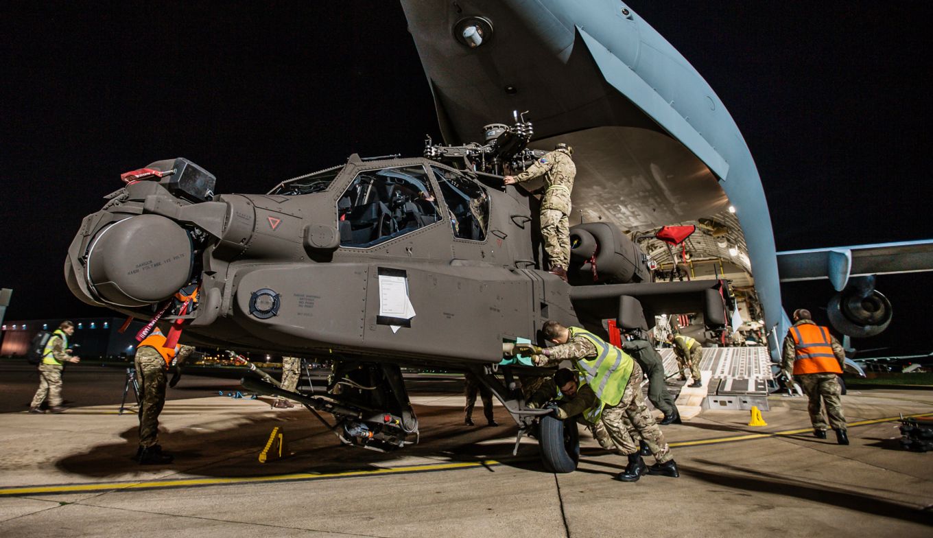 A British Army Apache AH-64E helicopter being unloaded from a C-17 at RAF Brize Norton after arriving from Kansas City