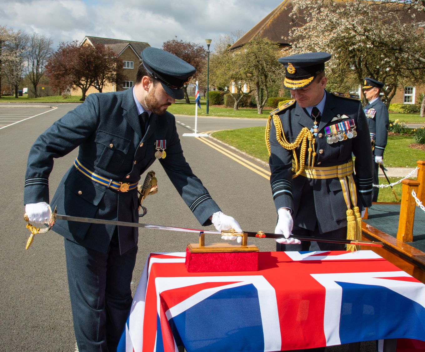 Flight Lieutenant Ben Burton, Parade Commander, along with the Chief of the Air Staff, Air Chief Marshal Sir Mike Wigston KCB CBE ADC unsheathes the Firmin Sword of Peace