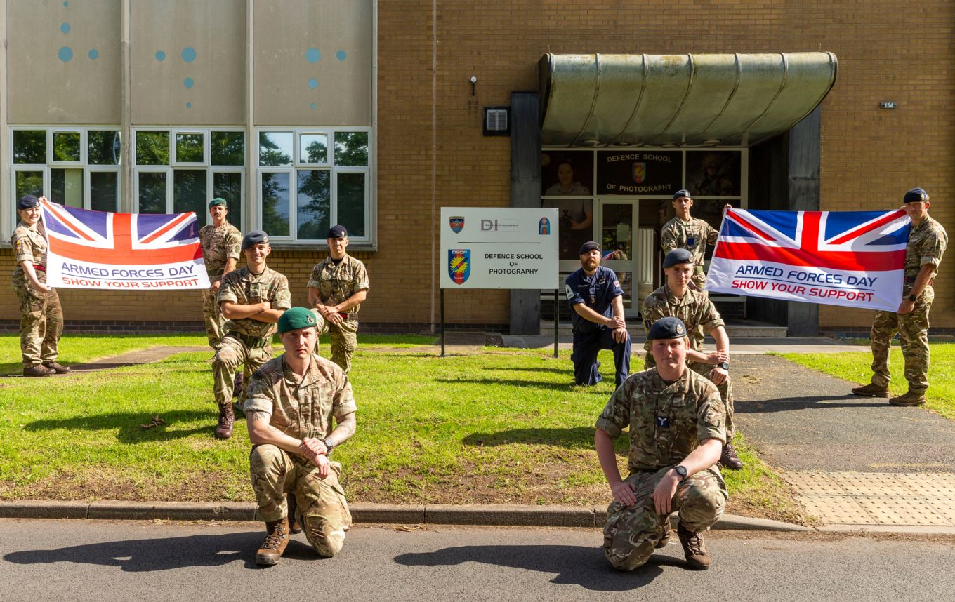 Students from the Defence School of Photography holding the Armed Forces Day Flag
