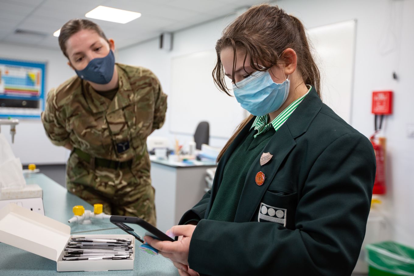 SAC Kayleigh Coleman from RAF Wittering assists a pupil with the Coronavirus app