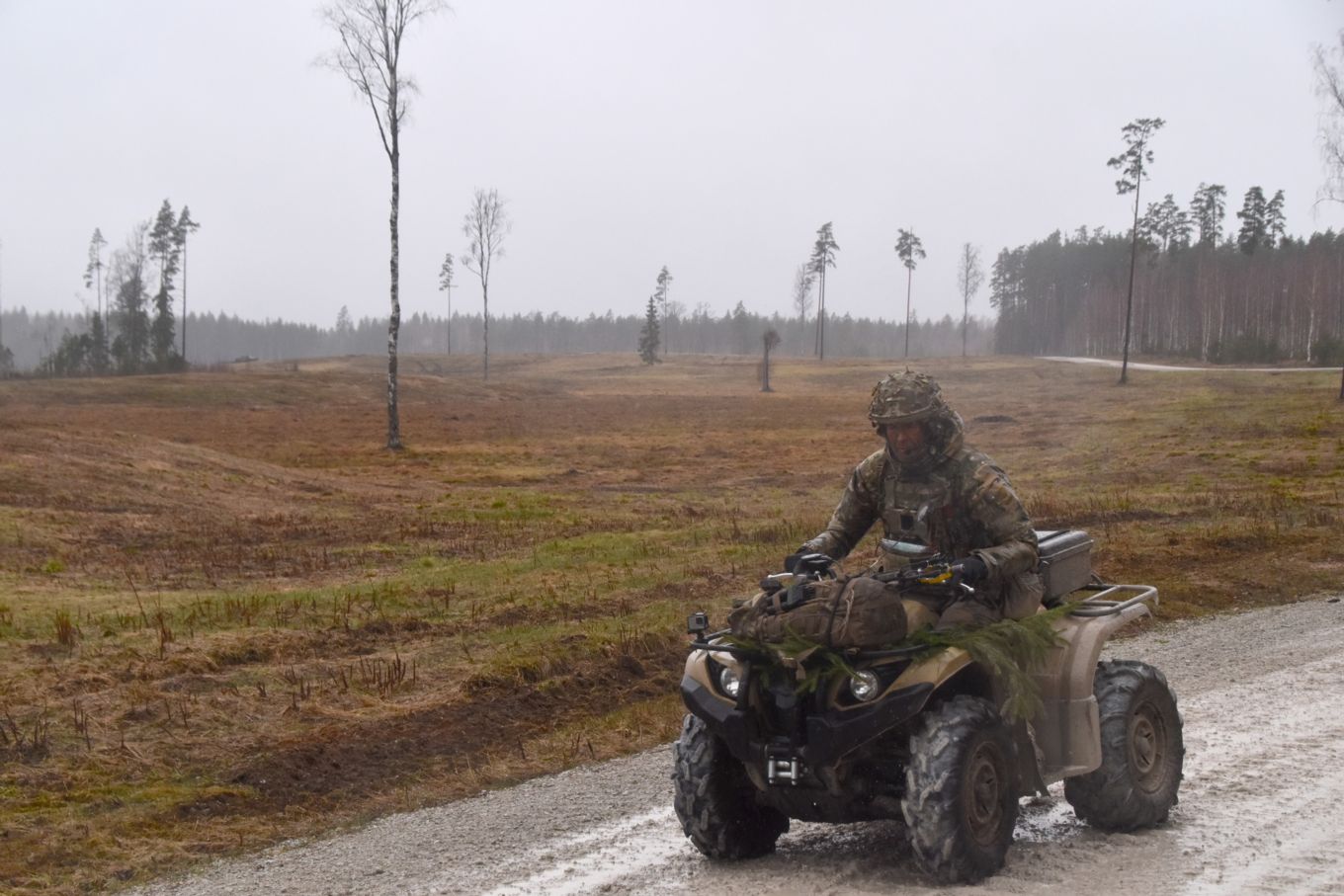 Personnel in greens driving quad bike vehicle.