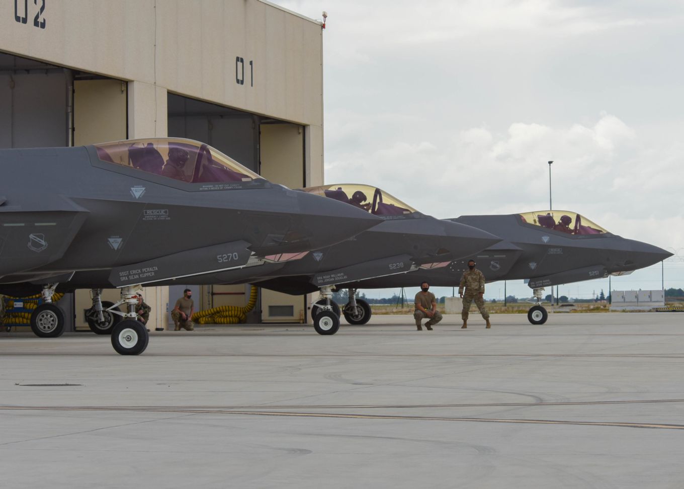 Three F-35B Lightnings on the ground with personnel and pilot.