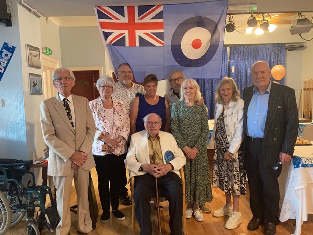 Squadron Leader John McGrory with friends and family and flag.