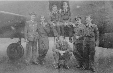 Black and white image of Squadron Leader John McGrory with personnel and aircraft.