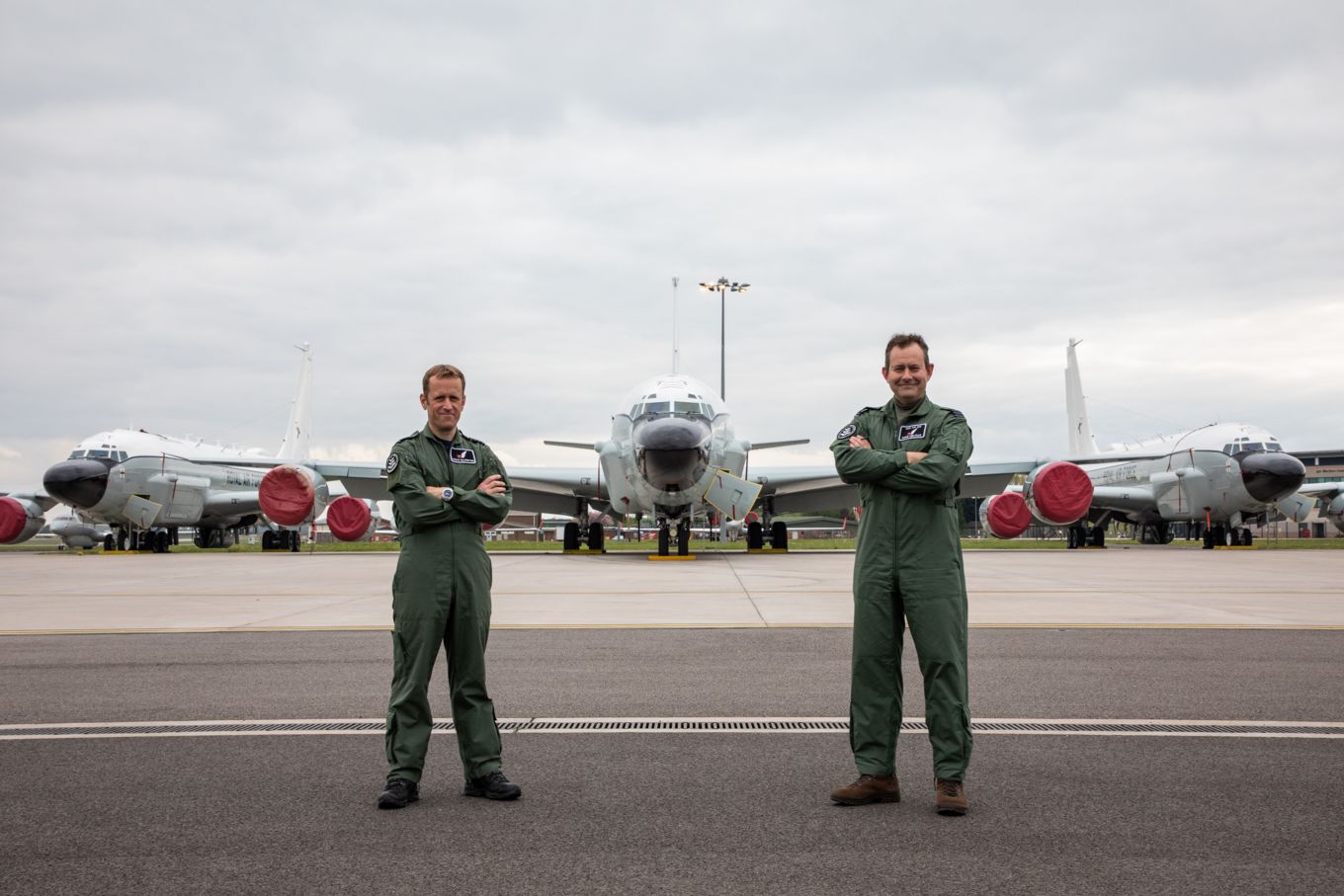 Group Captain Chris Melville and Group Captain Stephen Kilvington stand arms folded in-front of three planes. 