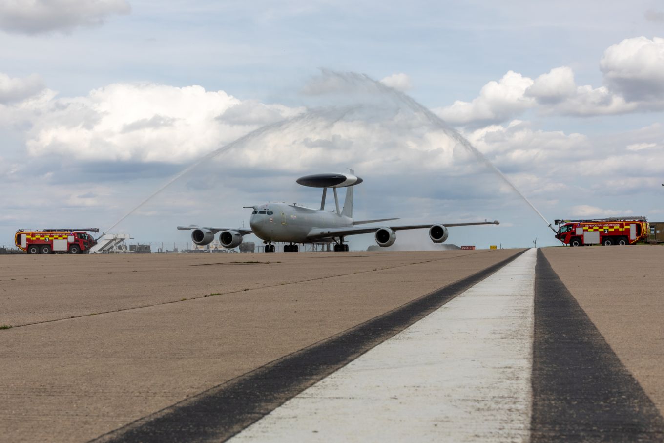 E-3D Sentry on the runway with water arch from emergency vehicles.