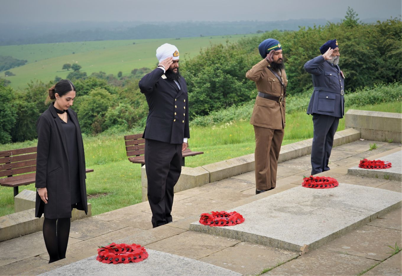 Personnel salute beside the wreaths.