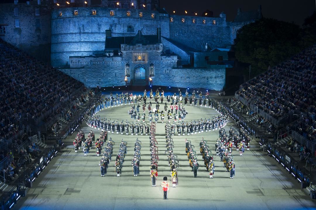 Pipes and Drums displaying in arena of Edinburgh Castle at night.