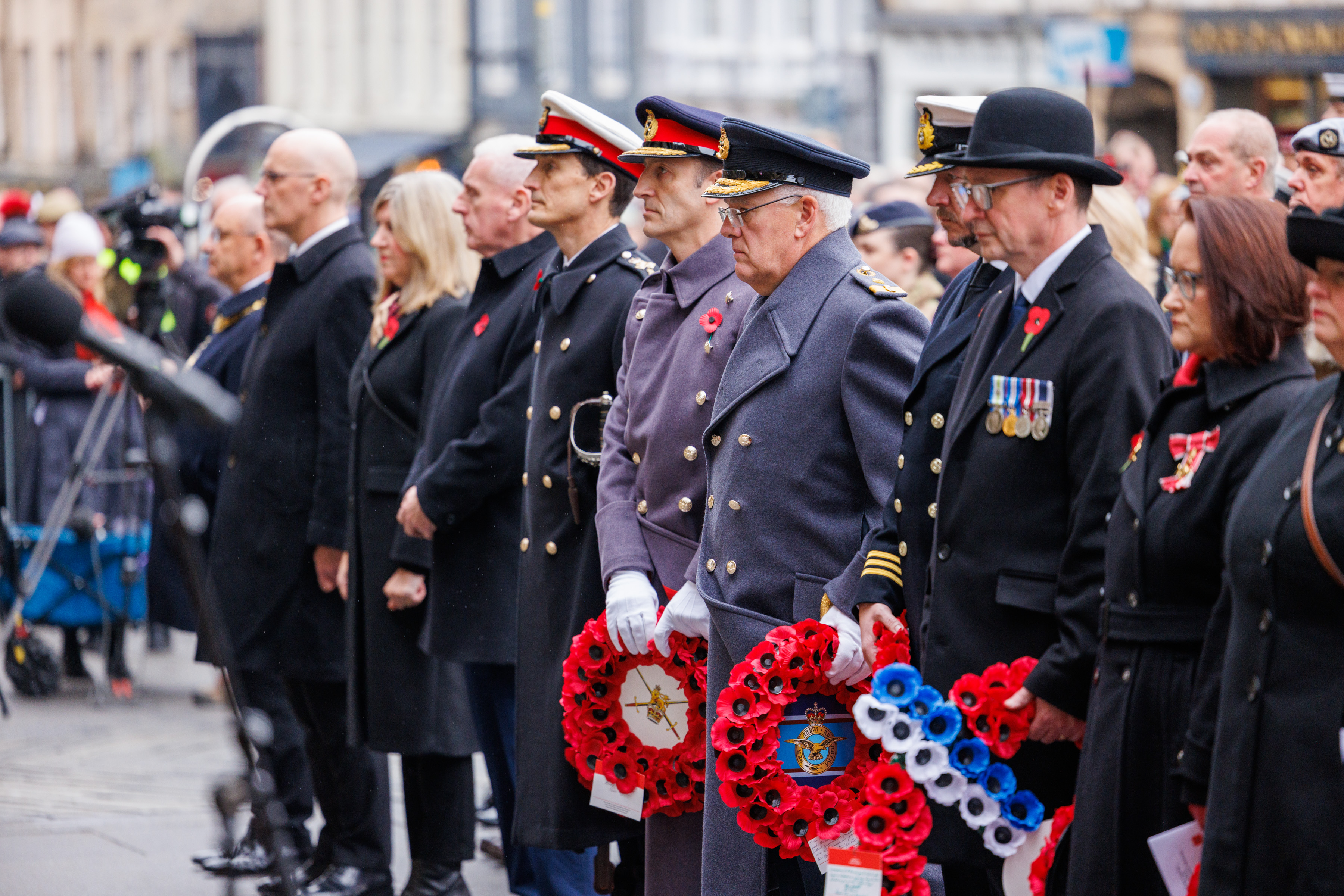 Armed Forces stand with poppy wreaths during service.