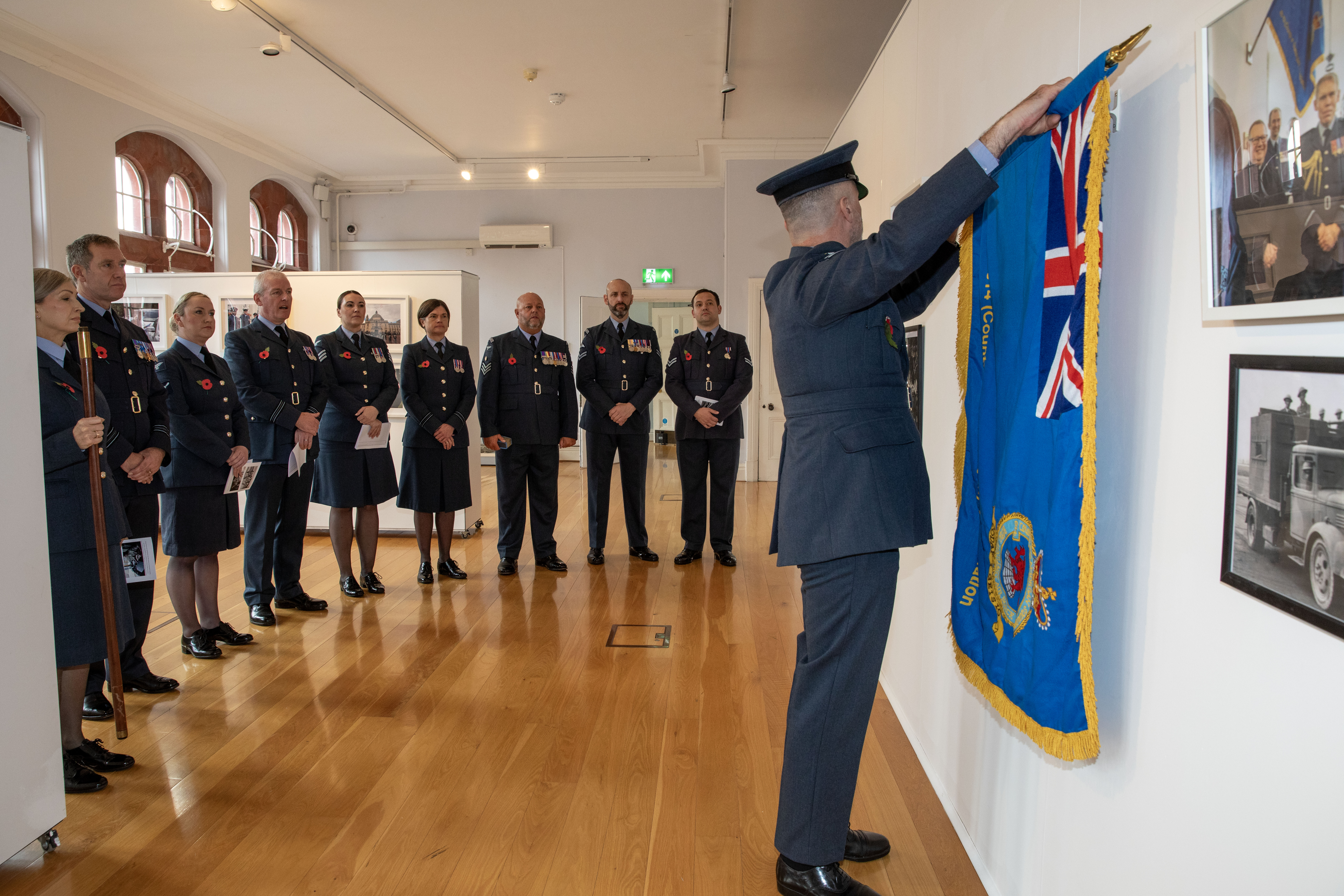 RAF Personnel stand before flag.