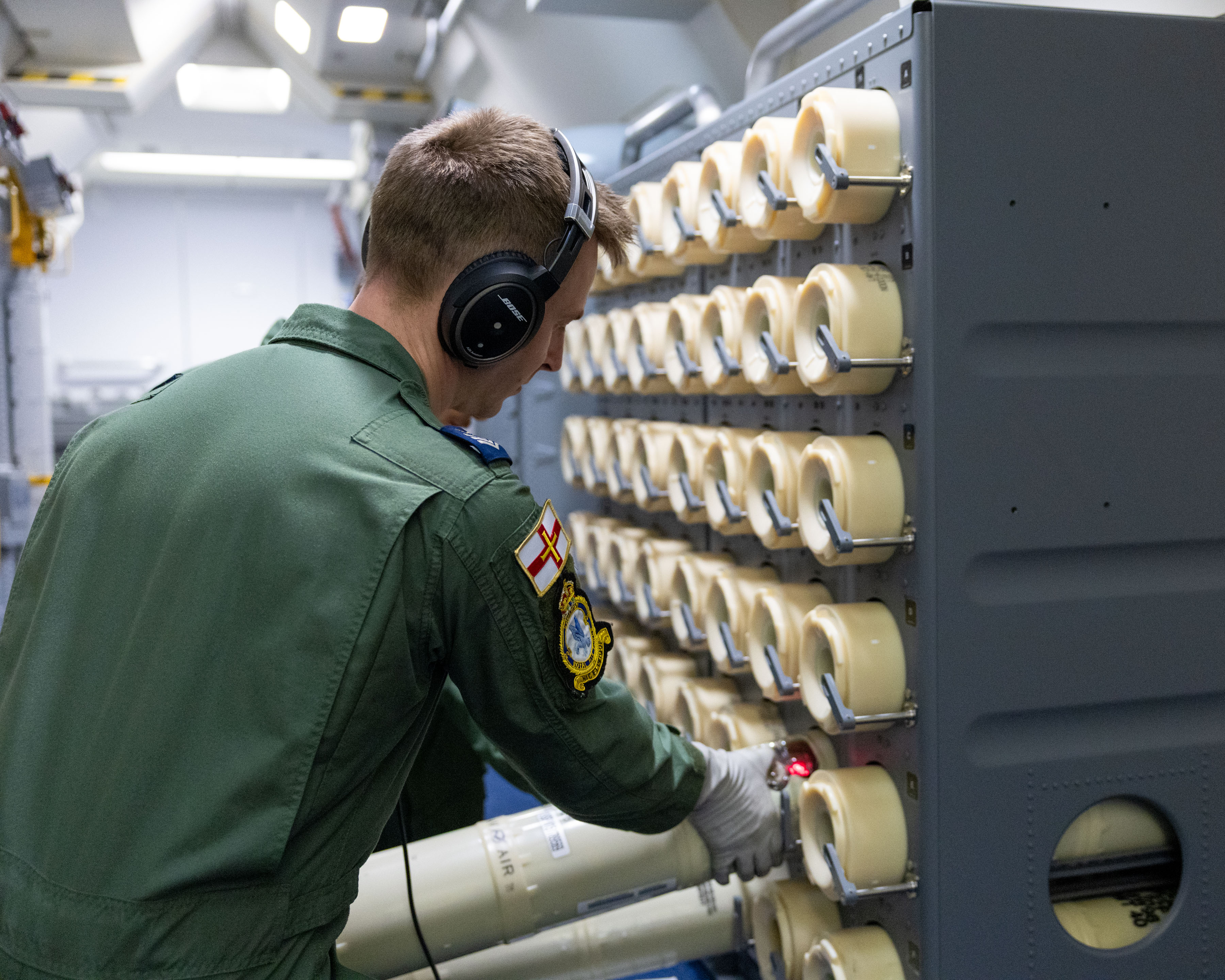 A member of an RAF Poseidon aircrew preparing a sonic buoy for launch.