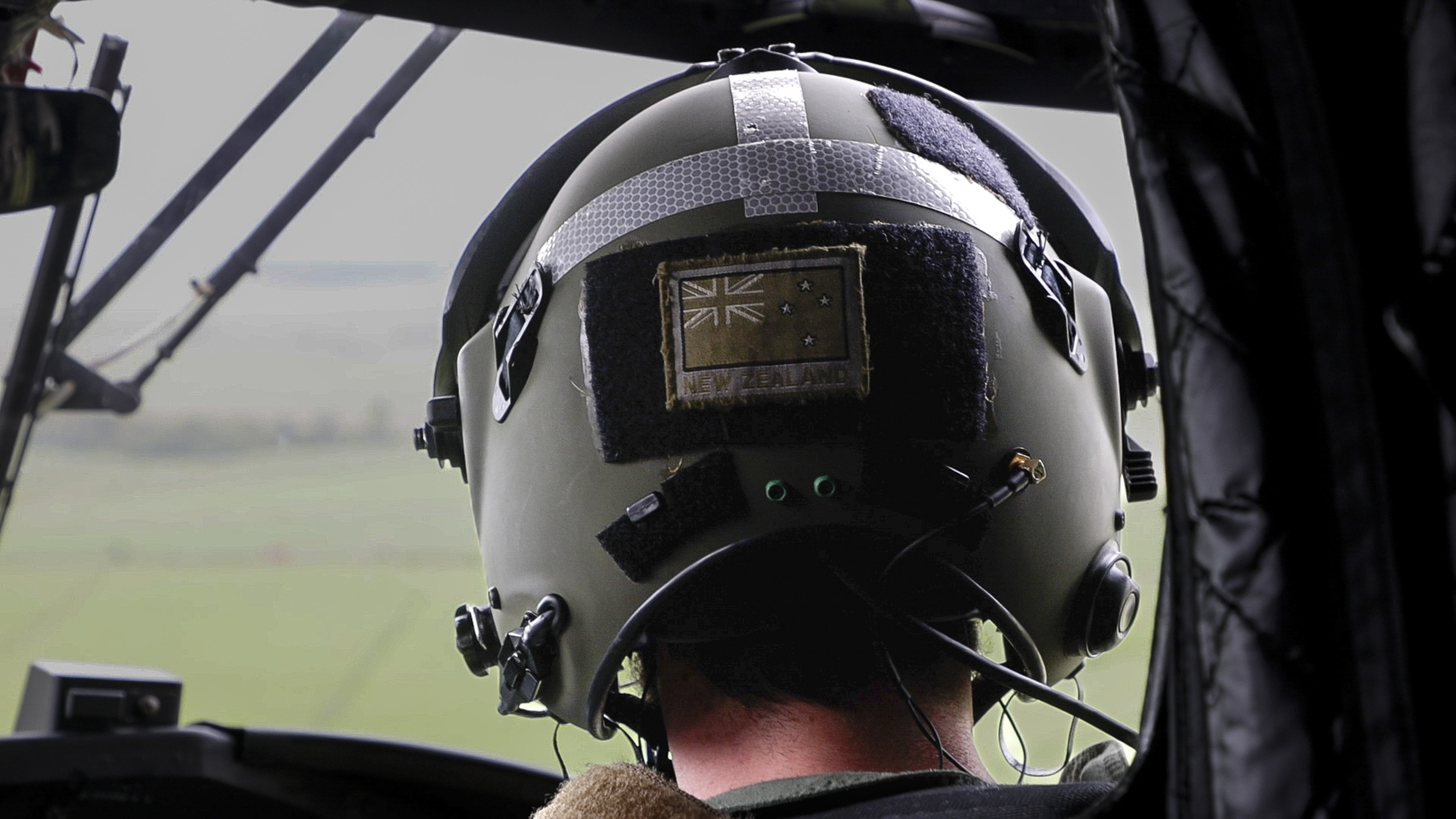 Back of the head of the New Zealand pilot as he flies the chinook, his New Zealand patch evident on the back of his flight helmet. 