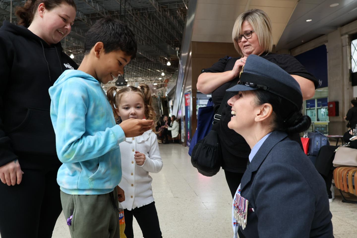 RAF personnel talking to a child who is holding a recently bough poppy.
