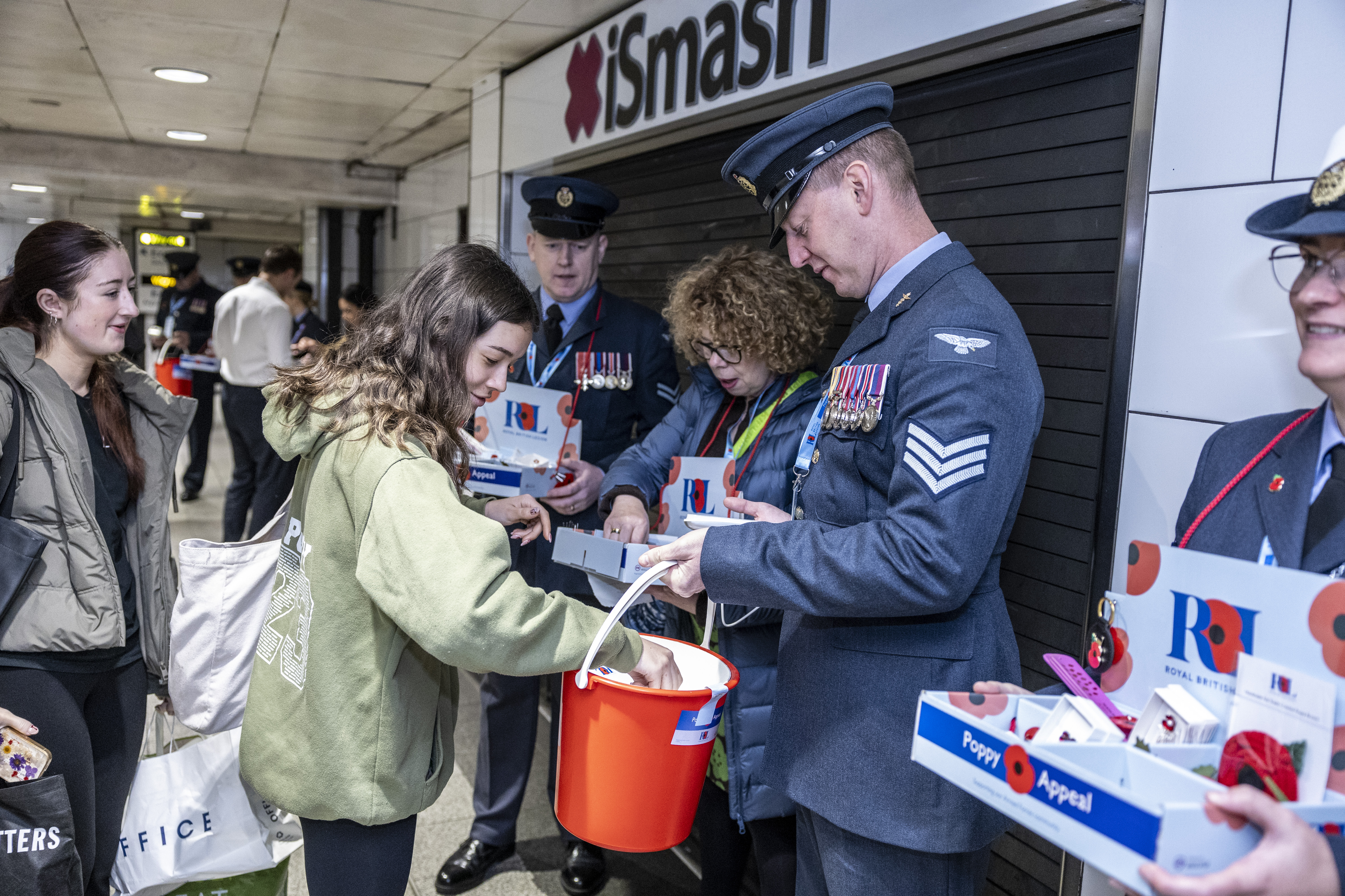 Young girl donating to RAF aviator holding donation bucket.