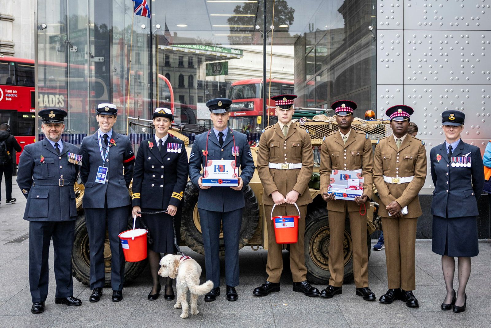 Tri-service personnel hold buckets and one has a dog.