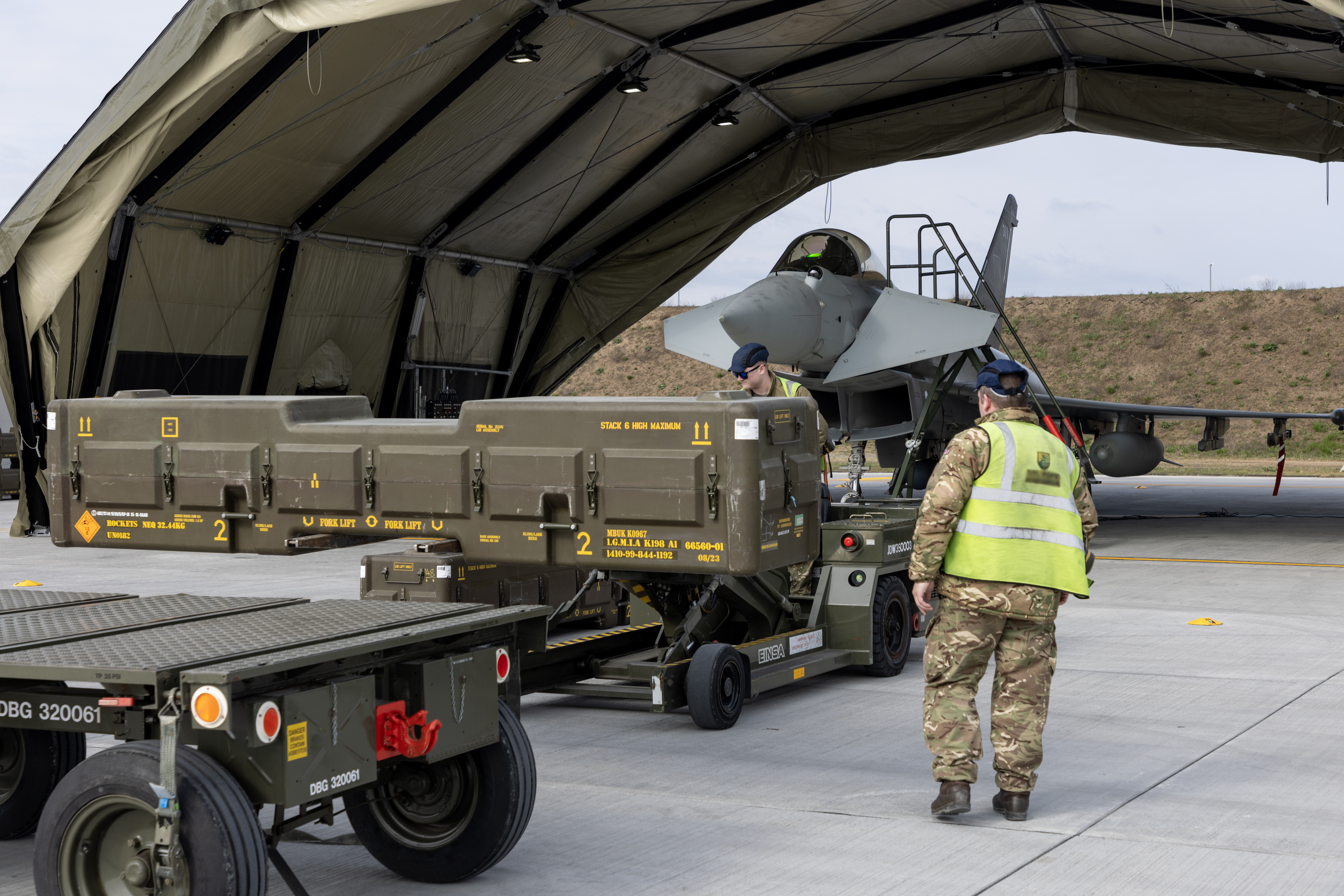 RAF ground crew transporting a large case holding Typhoon weaponry towards a hangar.