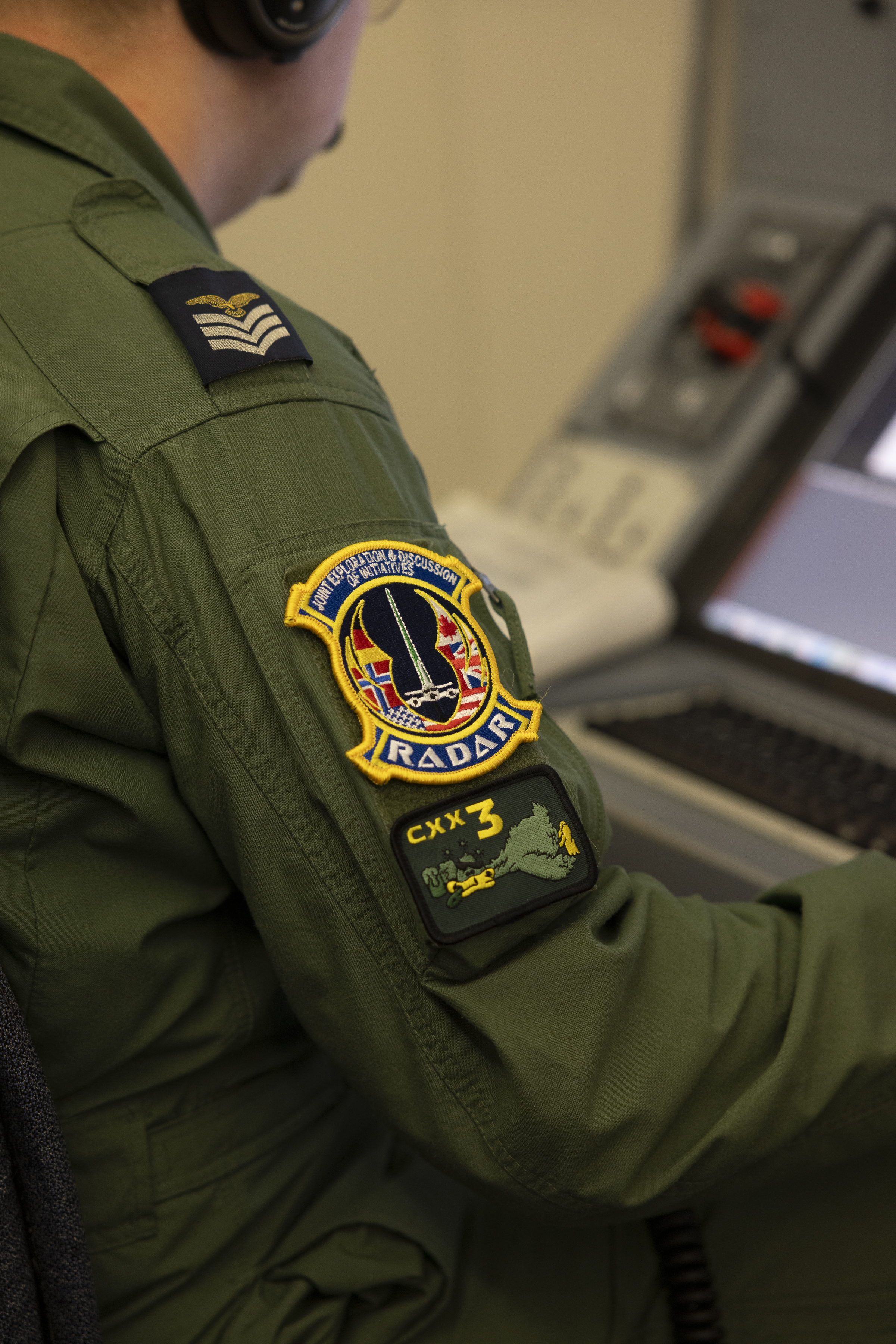 Side view of the arm and patches of a member of the Poseidon aircrew at their workstation on board the aircraft.