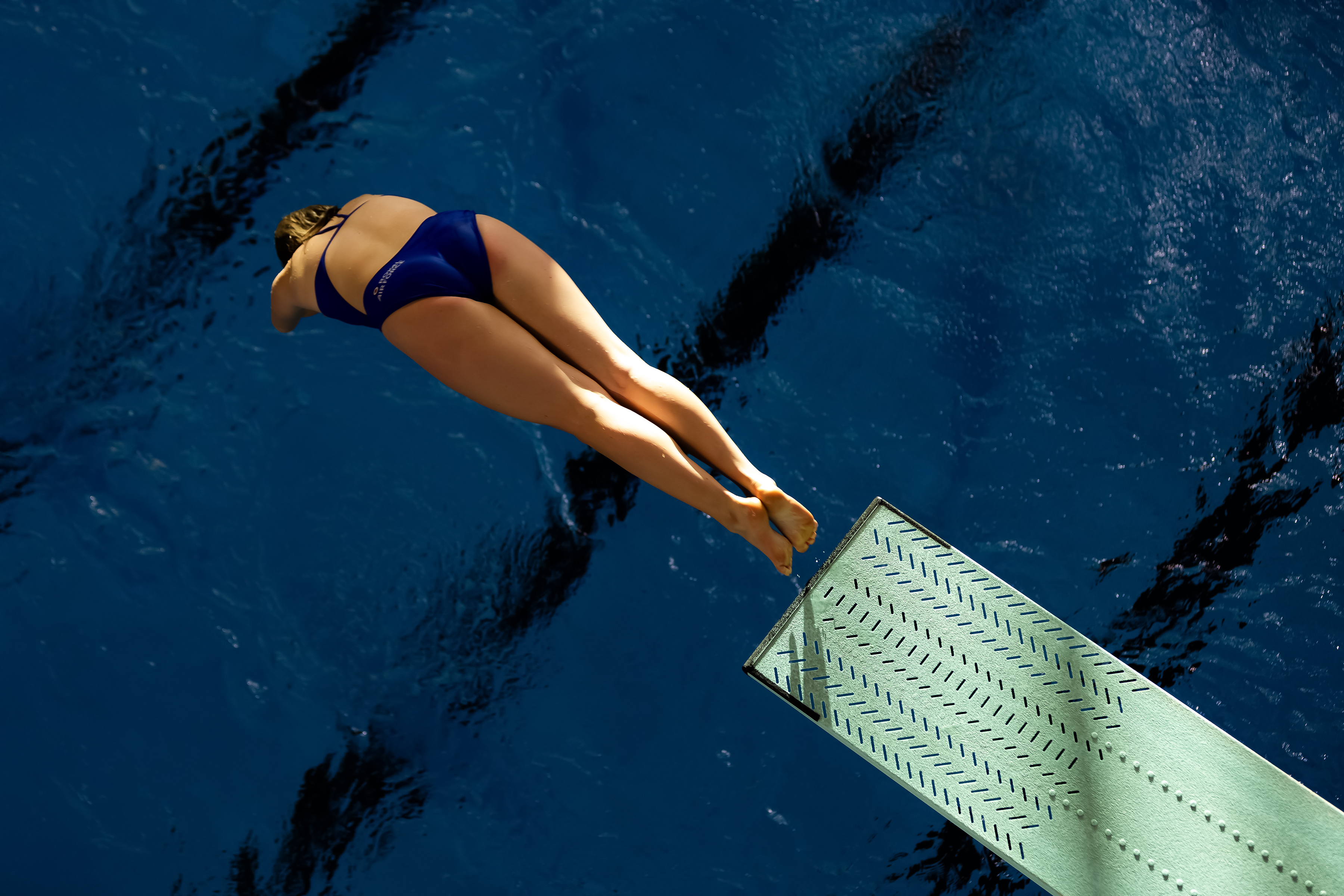 Female diving into a pool from a spring board.