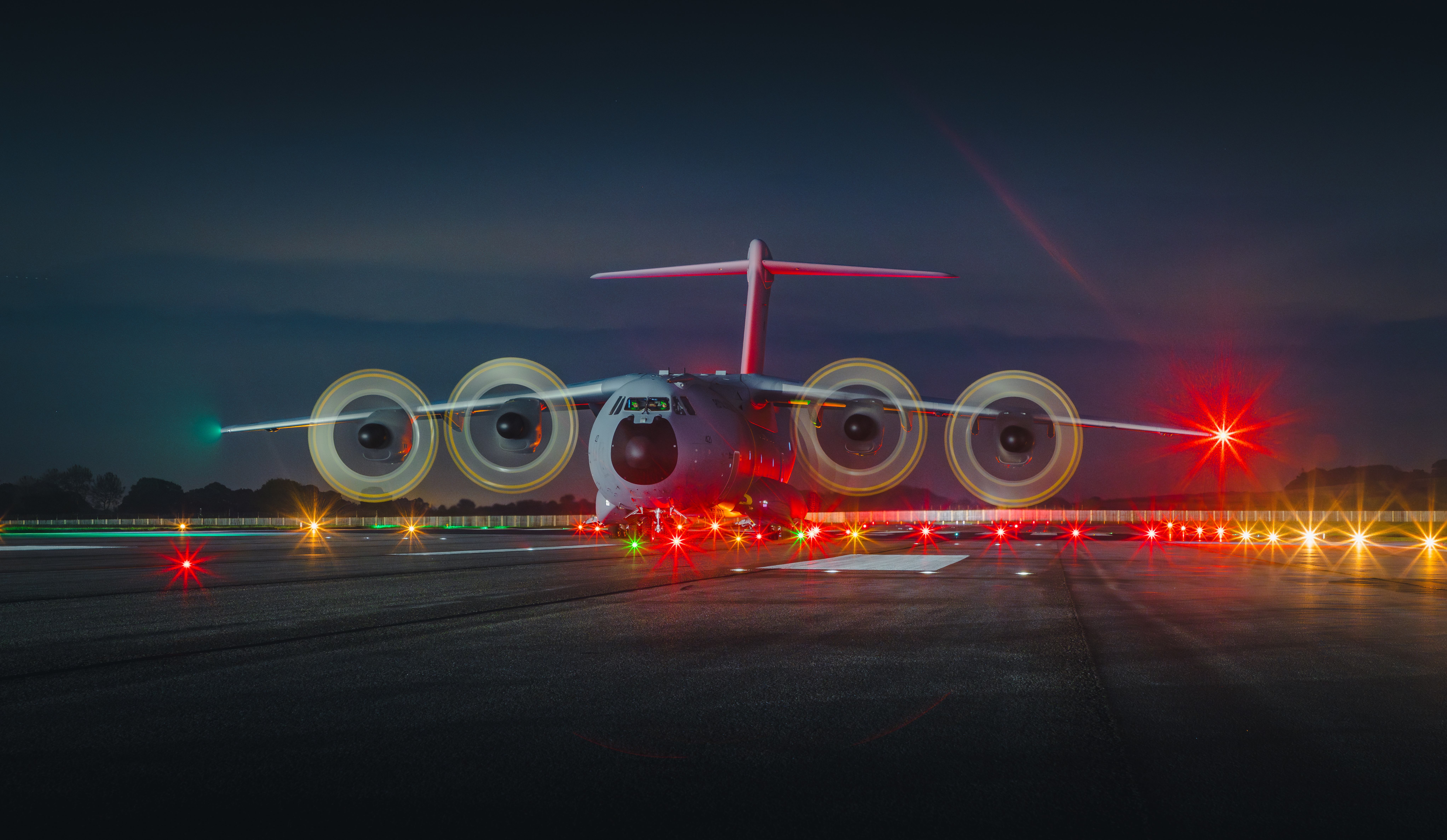 RAF Atlas aircraft on the airfield at night, with bright lights on. 