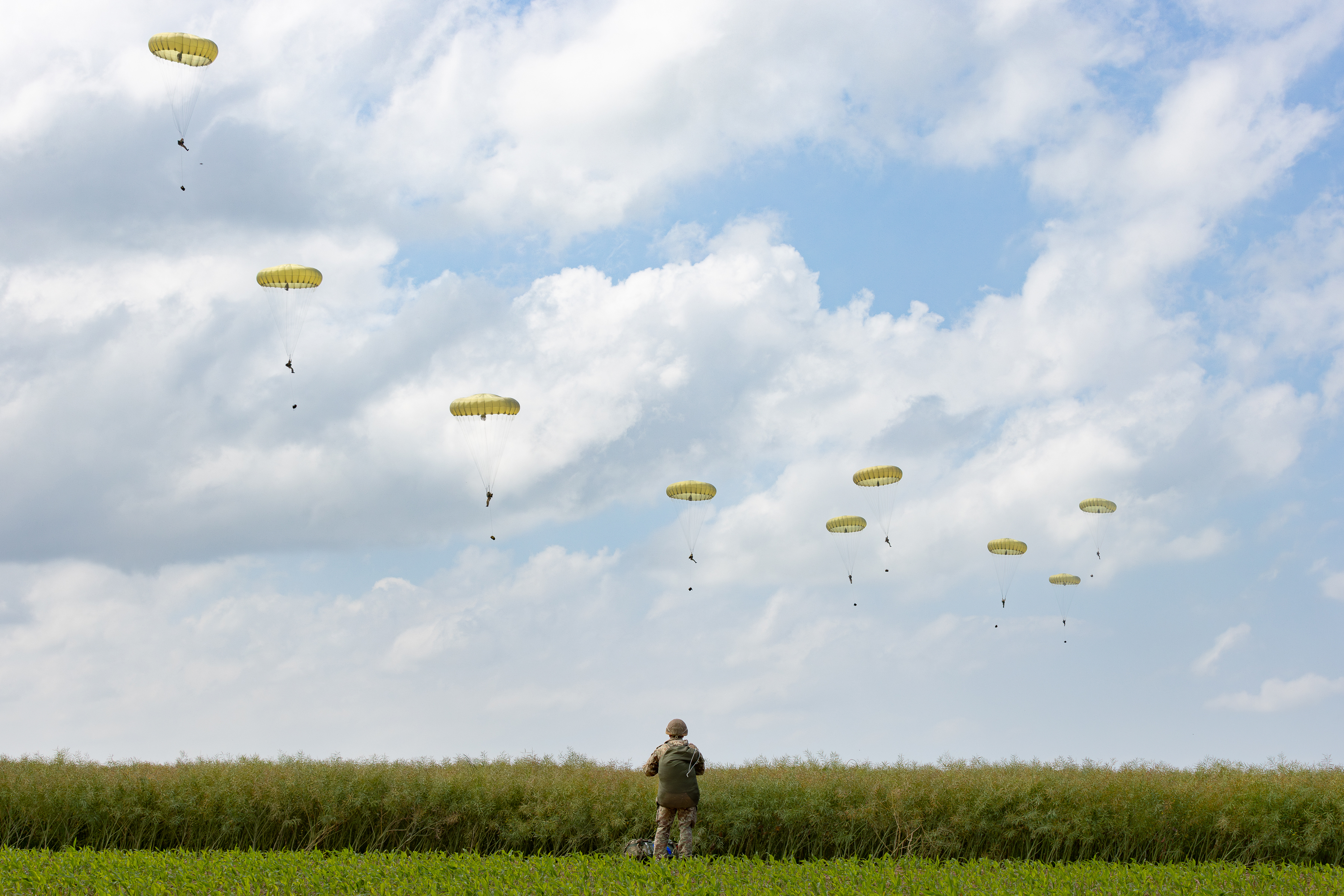 Parachutists coming into land in the distance.