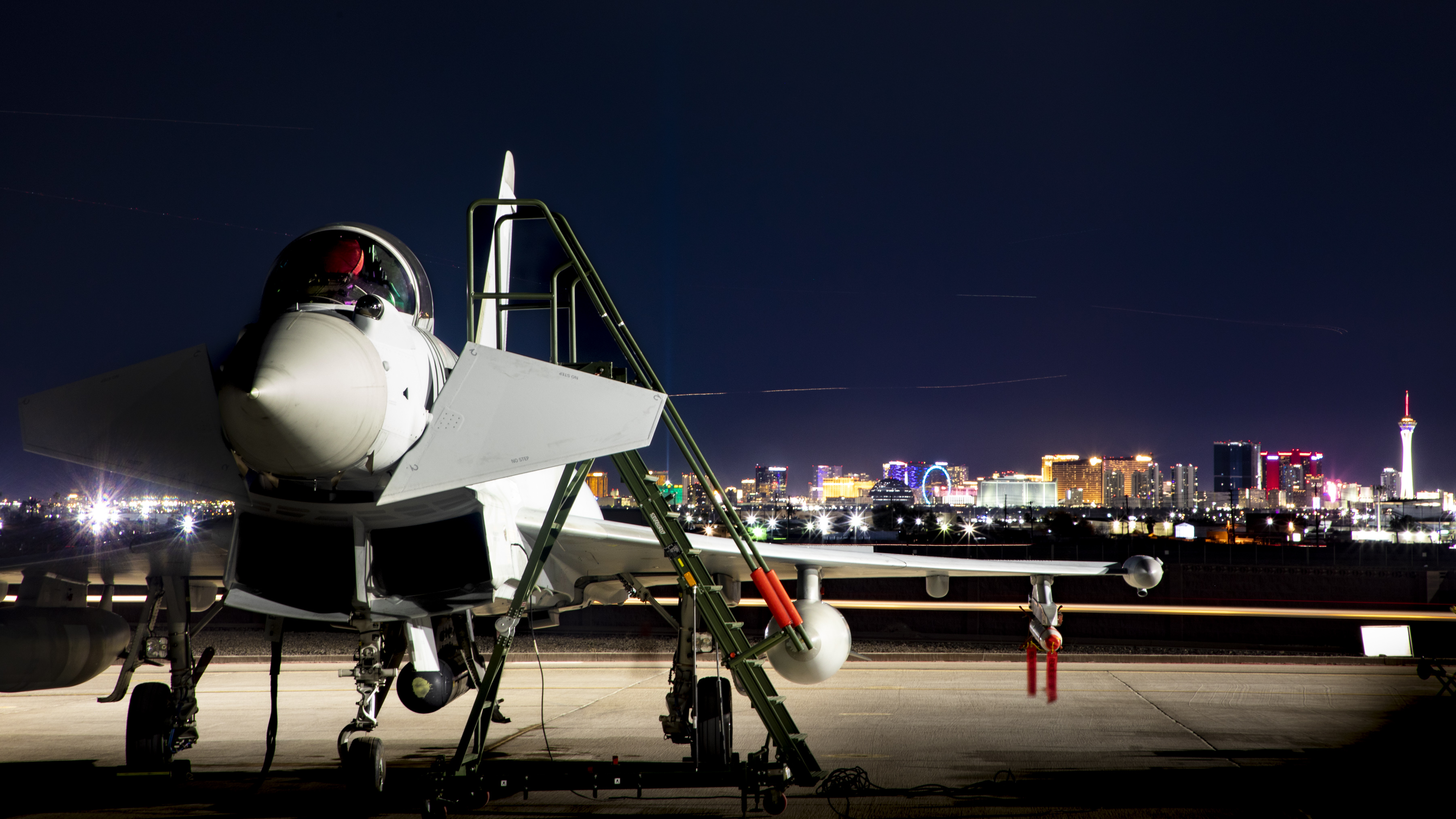 RAF Typhoon on runway at night, cityscape in background