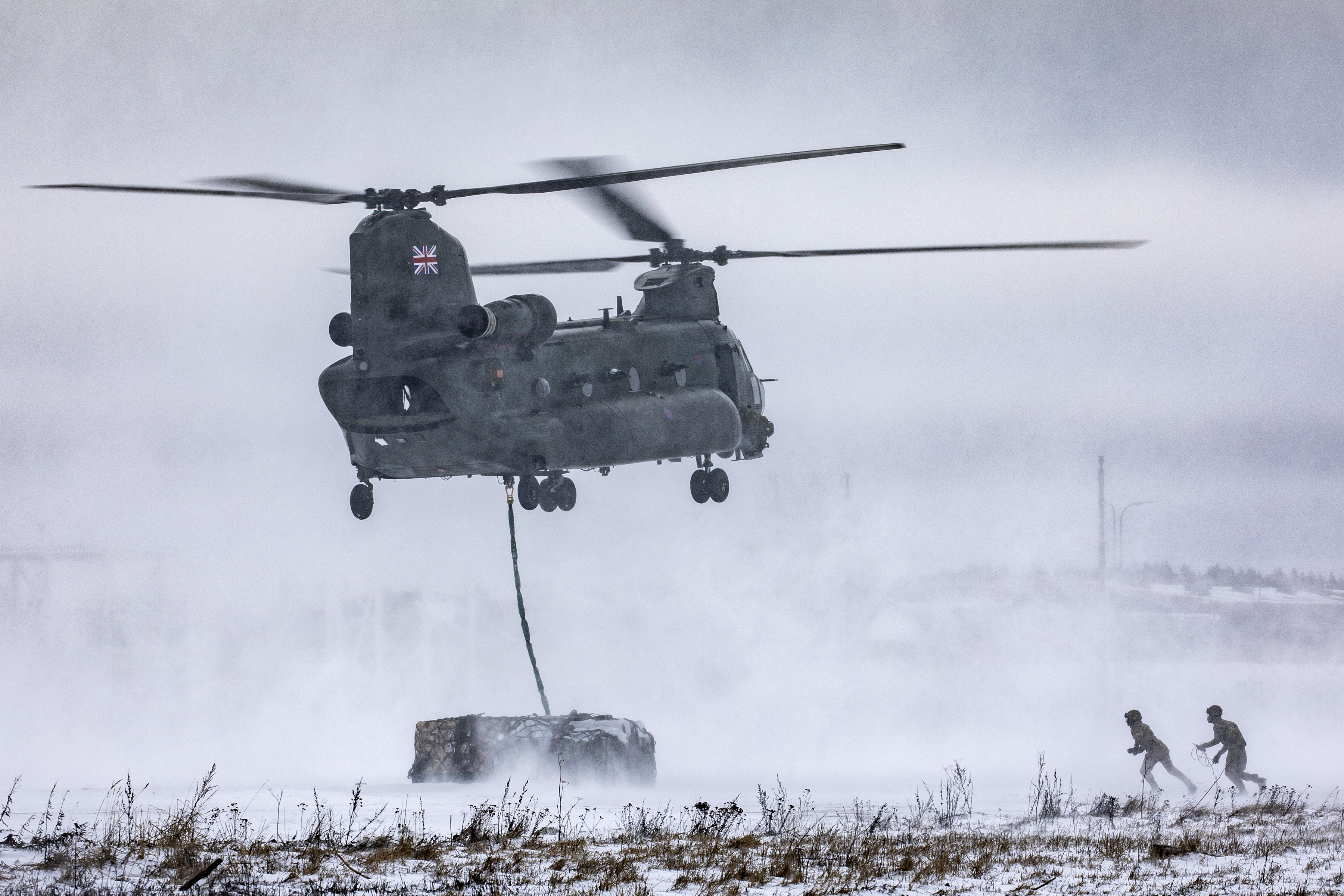 chinook dropping off underslung load, in the snow. 
