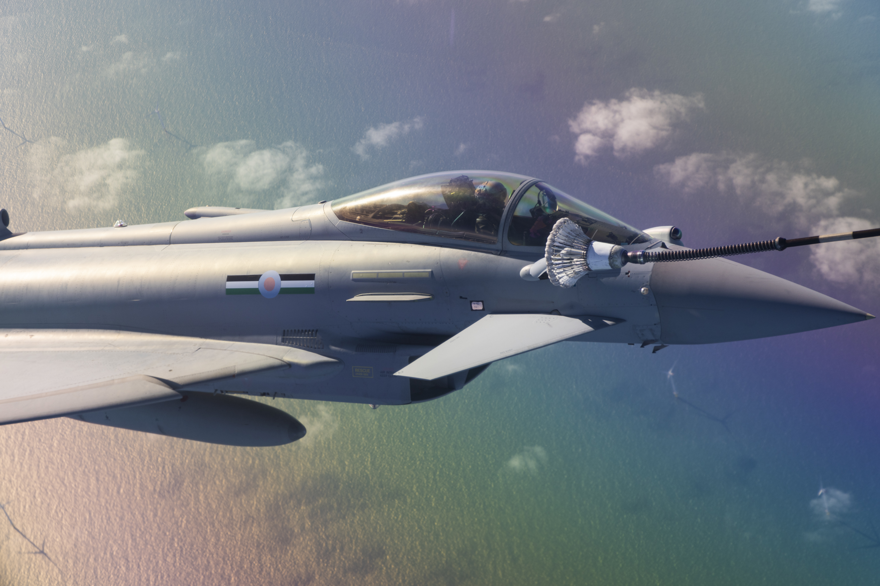 Typhoon taking an air-to-air refuel, ocean background reflecting like a rainbow
