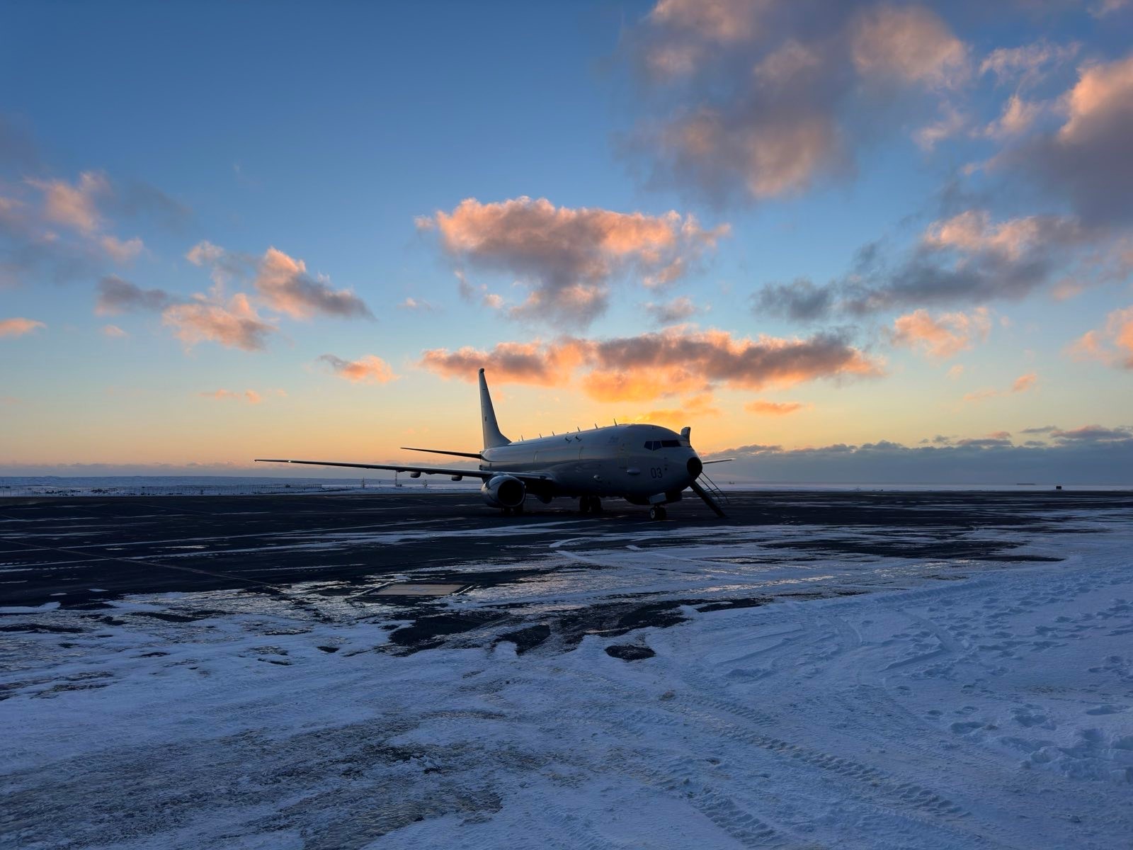 Poseidon on the runway, with the sun reflecting off clouds in the background in various hues.