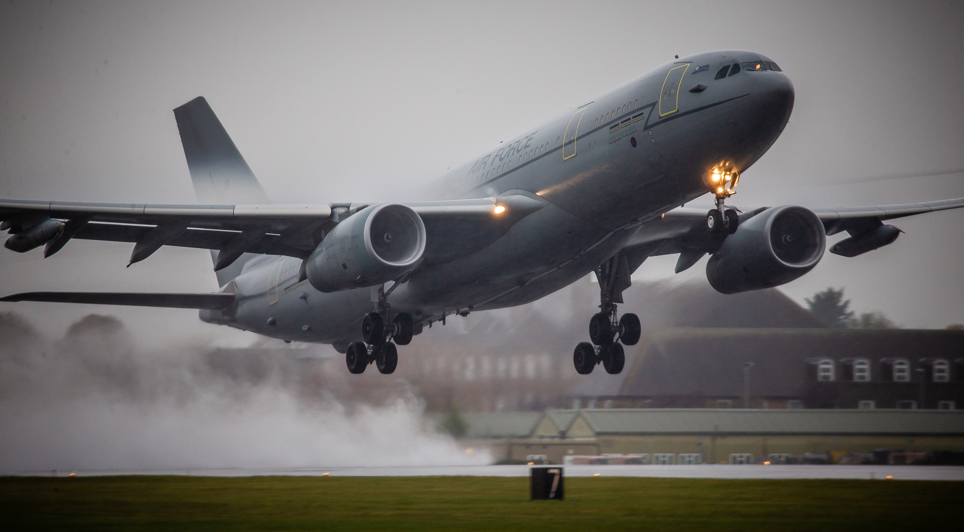An RAF Voyager taking off from a runway in grey, rainy weather.