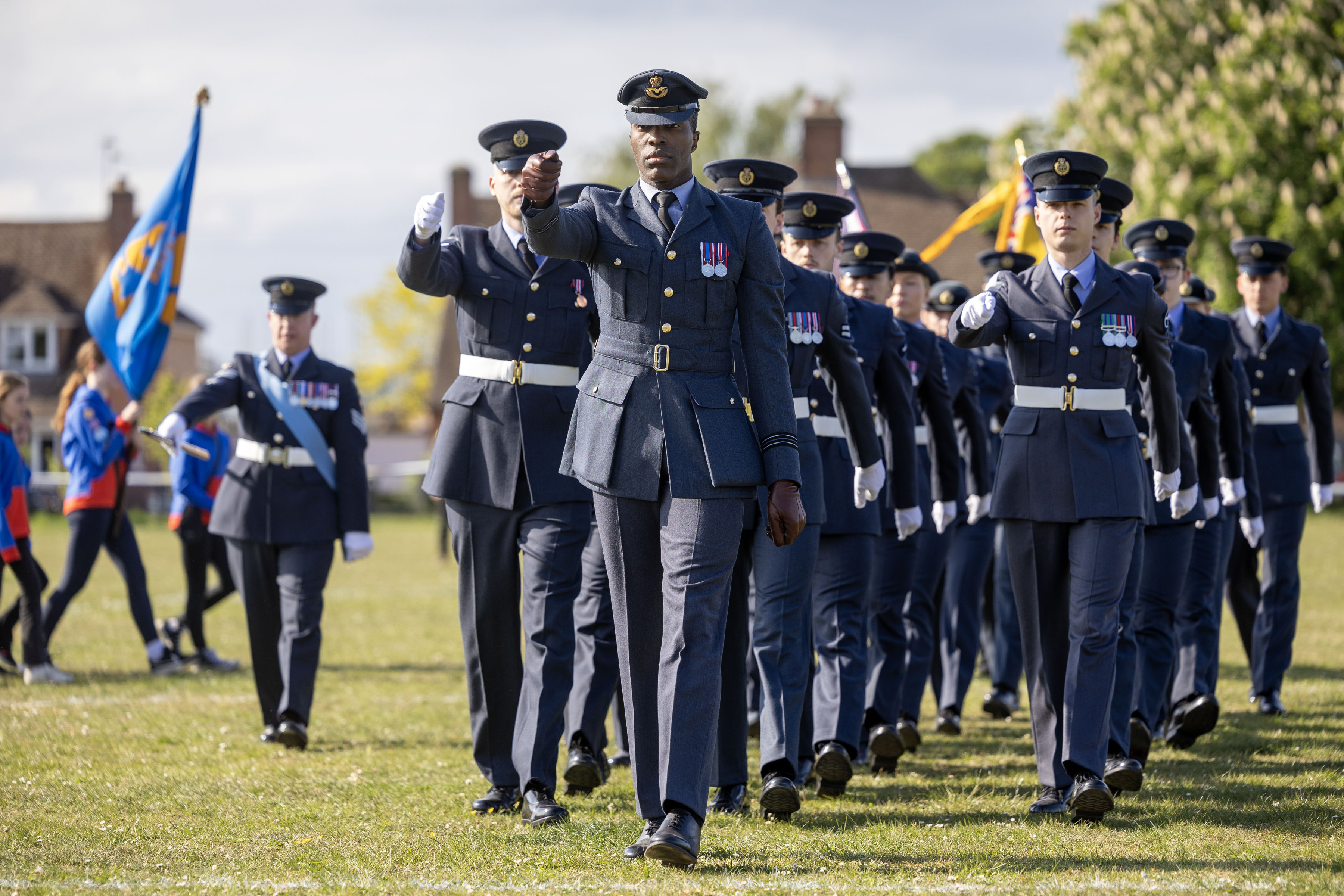A Flight Lieutenant leading a parade marching on grass.