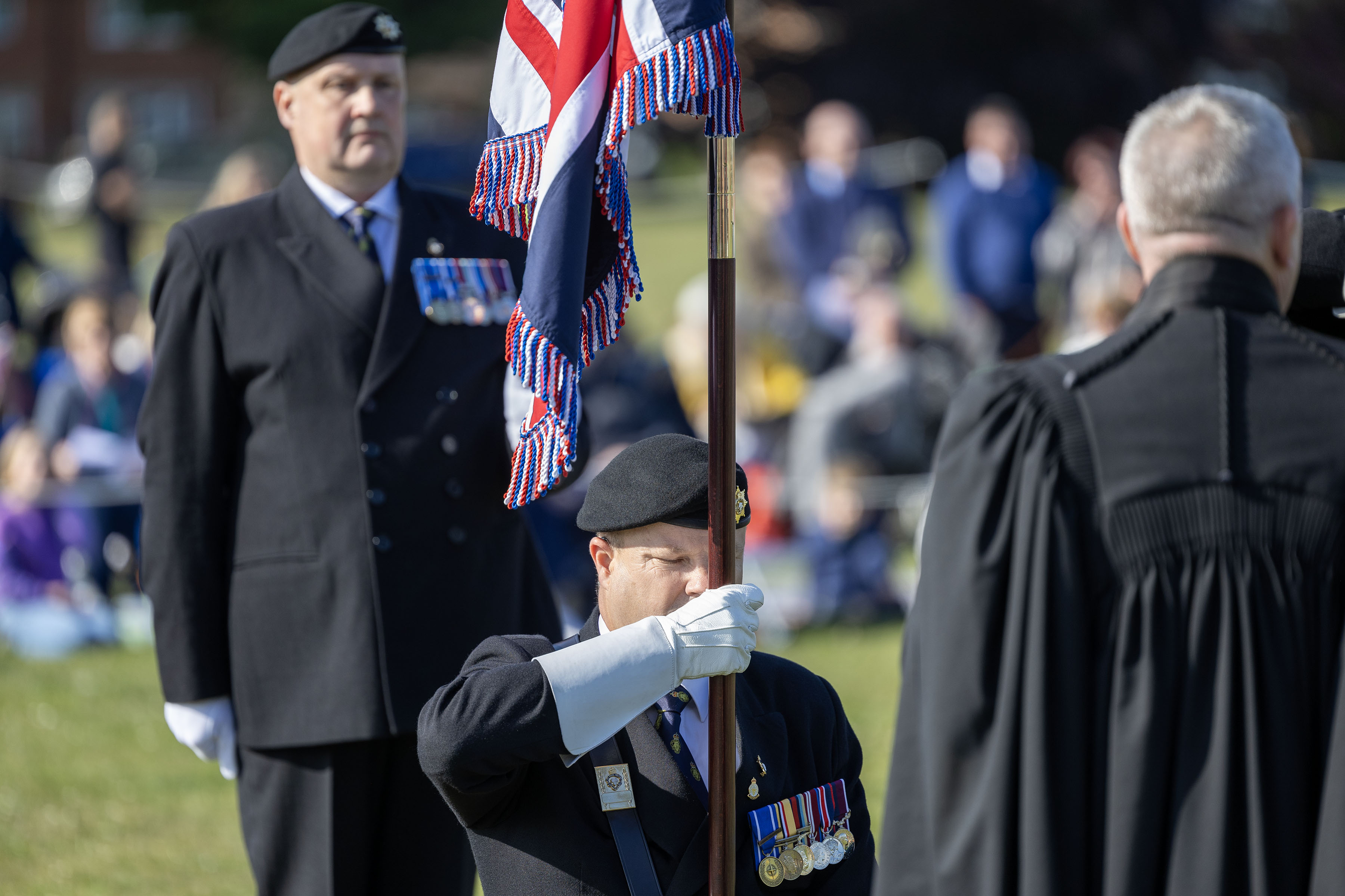 Royal British Legion member kneeling with the Union Flag for the blessing at the field alter. 