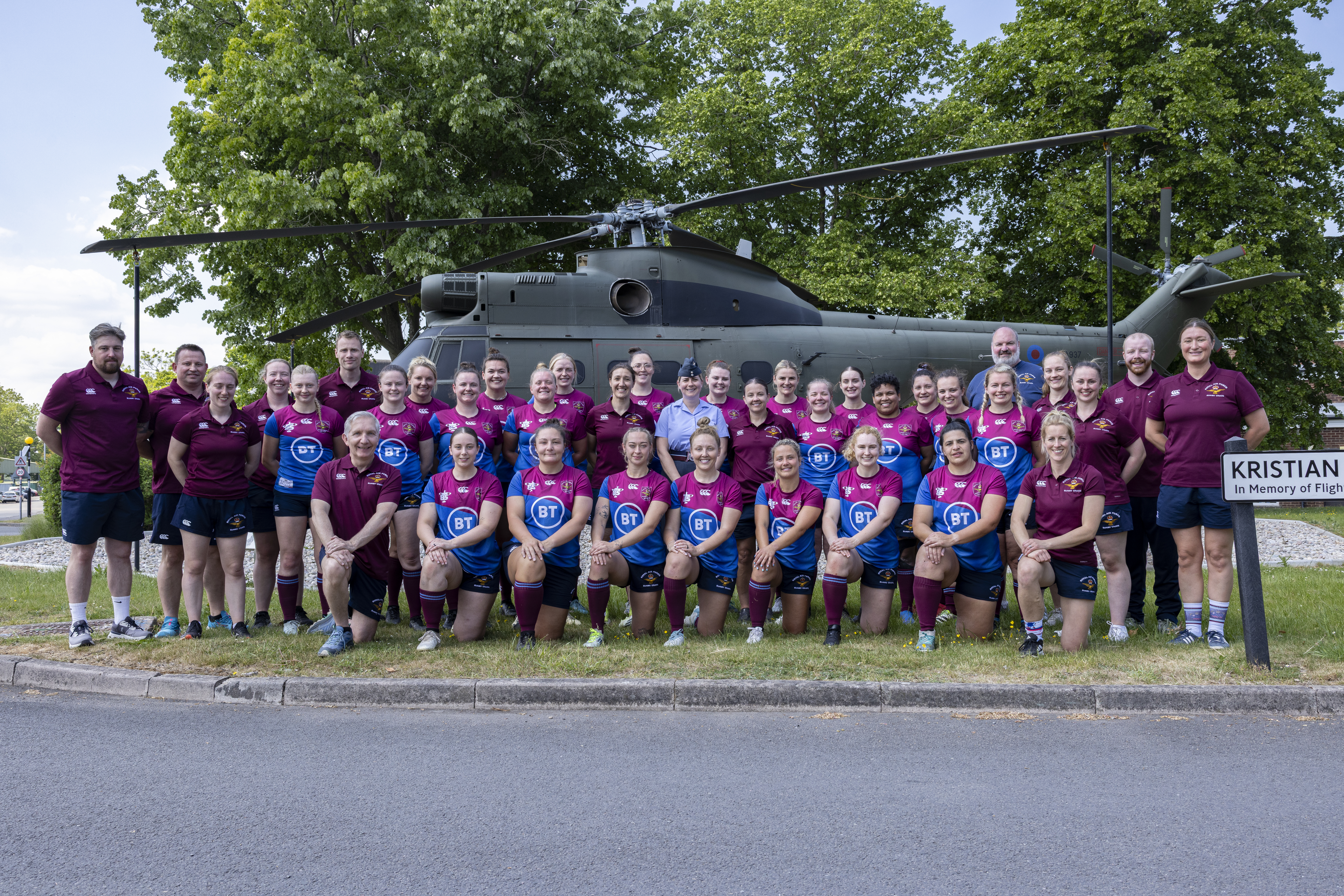 RAF Rugby Union Women's Senior squad, coaches and RAF Benson Station Commander stand for a photograph in front of the RAF Benson Puma helicopter gate guardian.