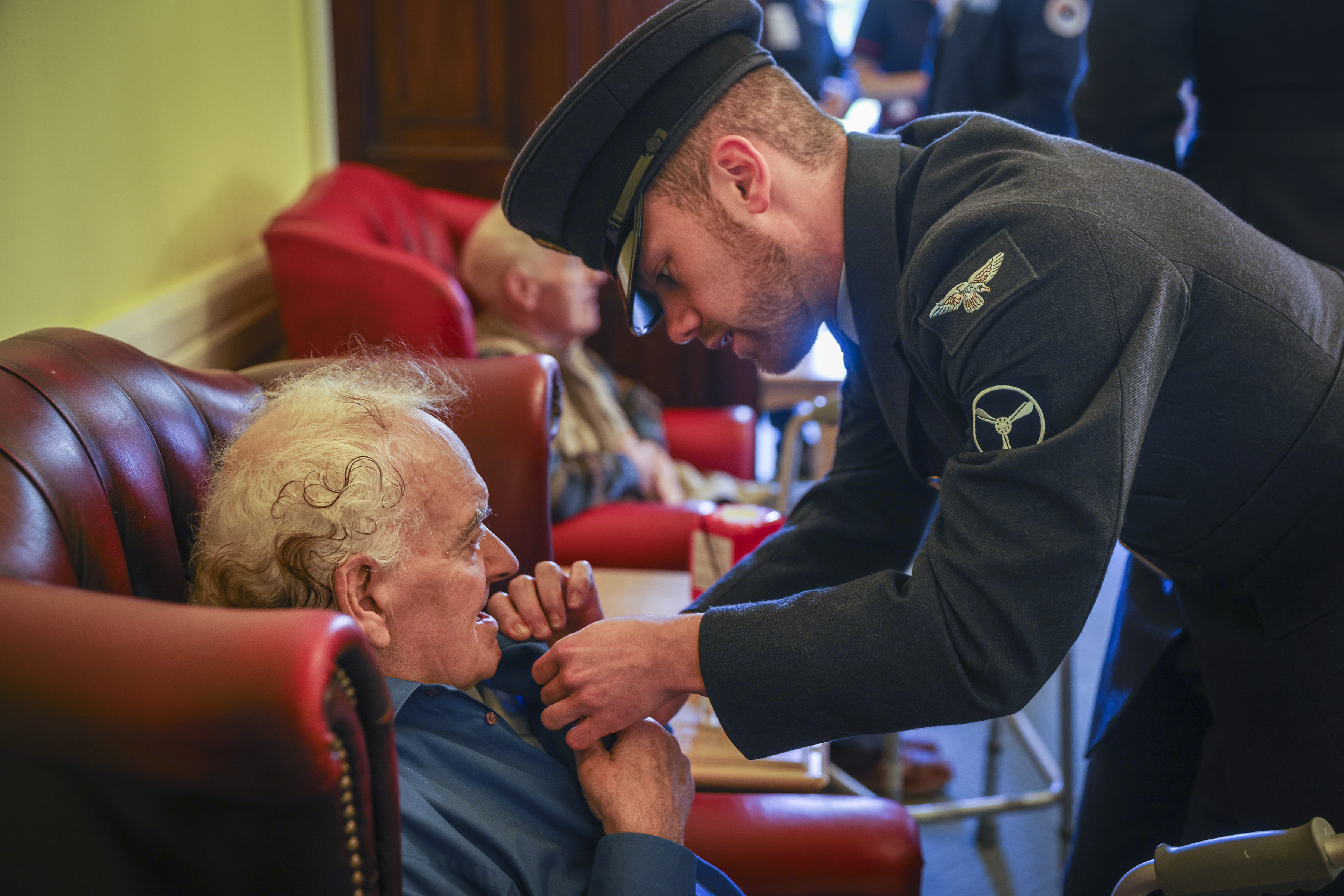 A AS1(T) Class 1 helps a veteran display their poppy on their chest at the local care home. 