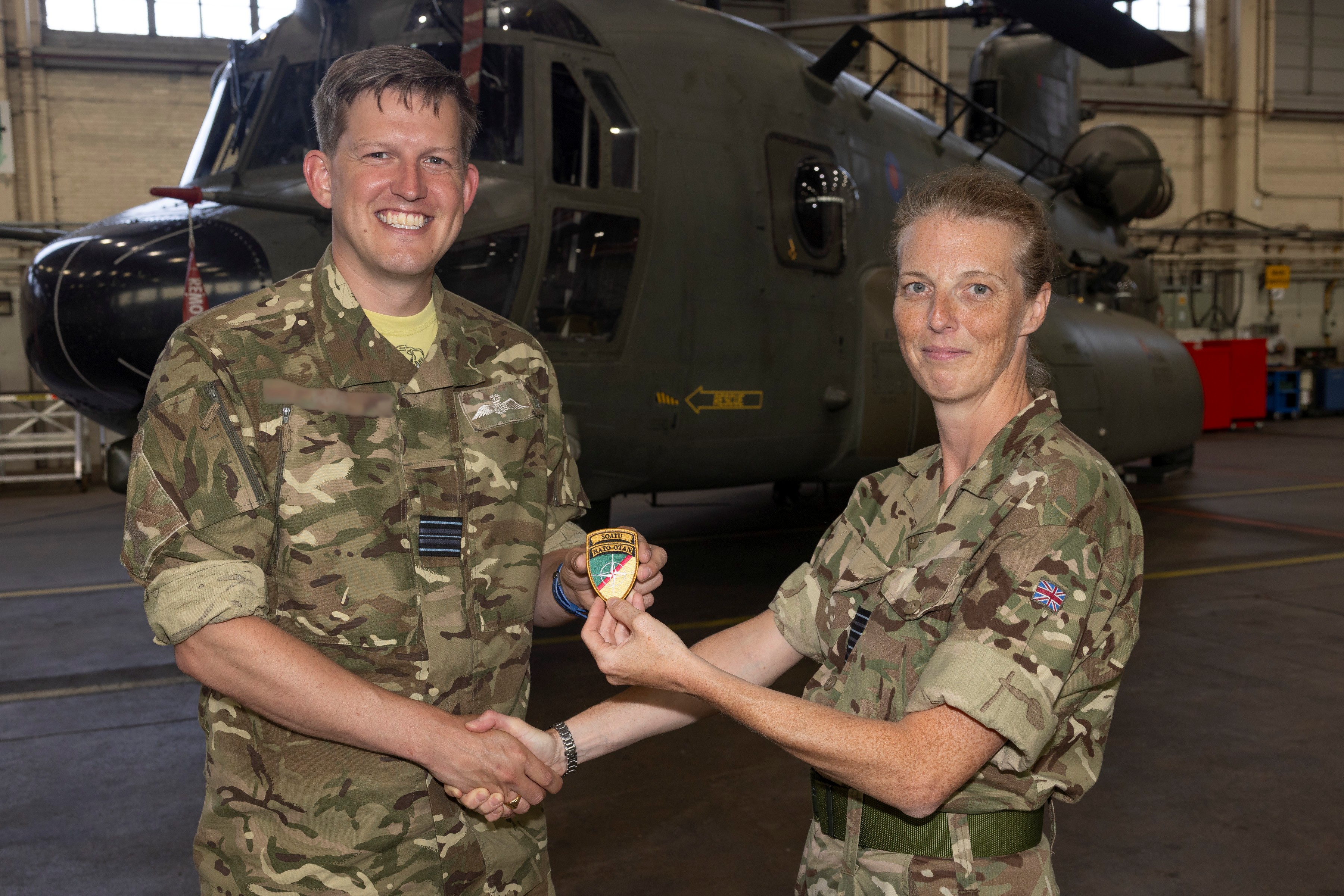 Chinook Force Commander, Group Captain Hannah Bishop, presents the new NATO patch to a member of 27 Squadron