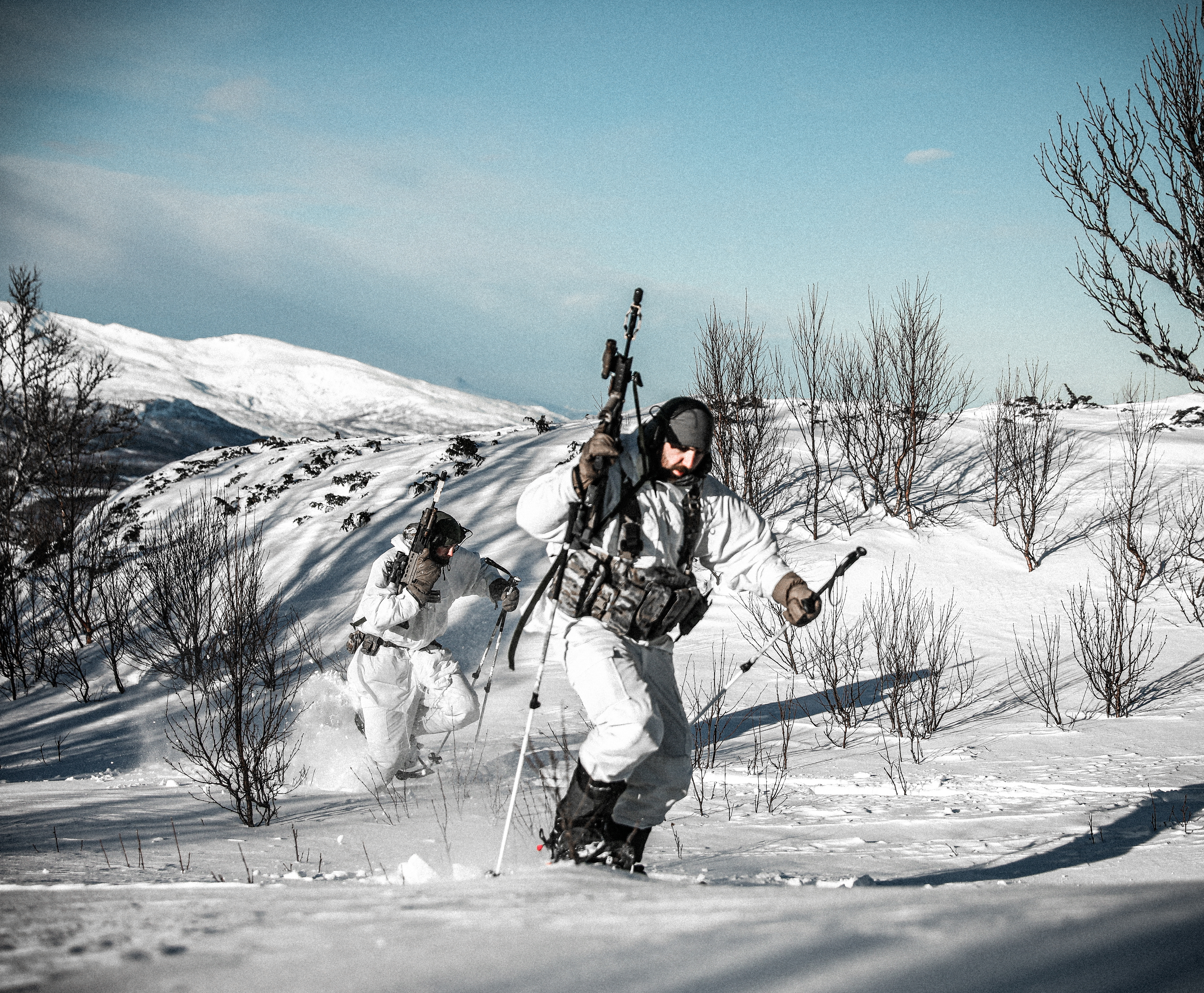 Members of the RAF Regiment using ski poles to traverse quickly up a snowy slope.