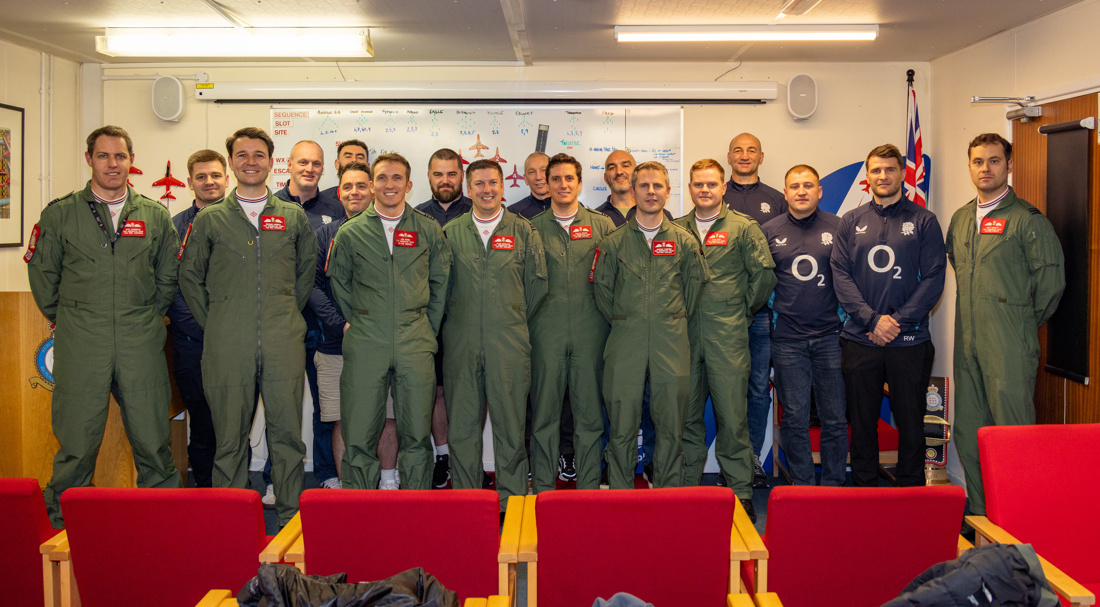 The England and Red Arrows teams stand together in a briefing room at RAF Waddington.